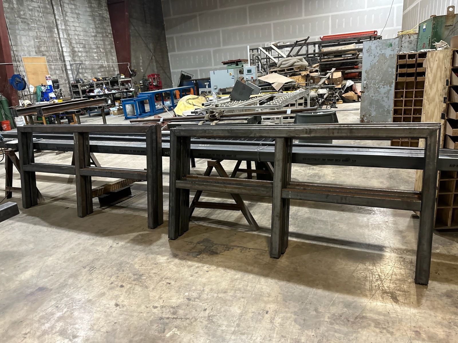 Two unfinished metal console tables in a workshop.