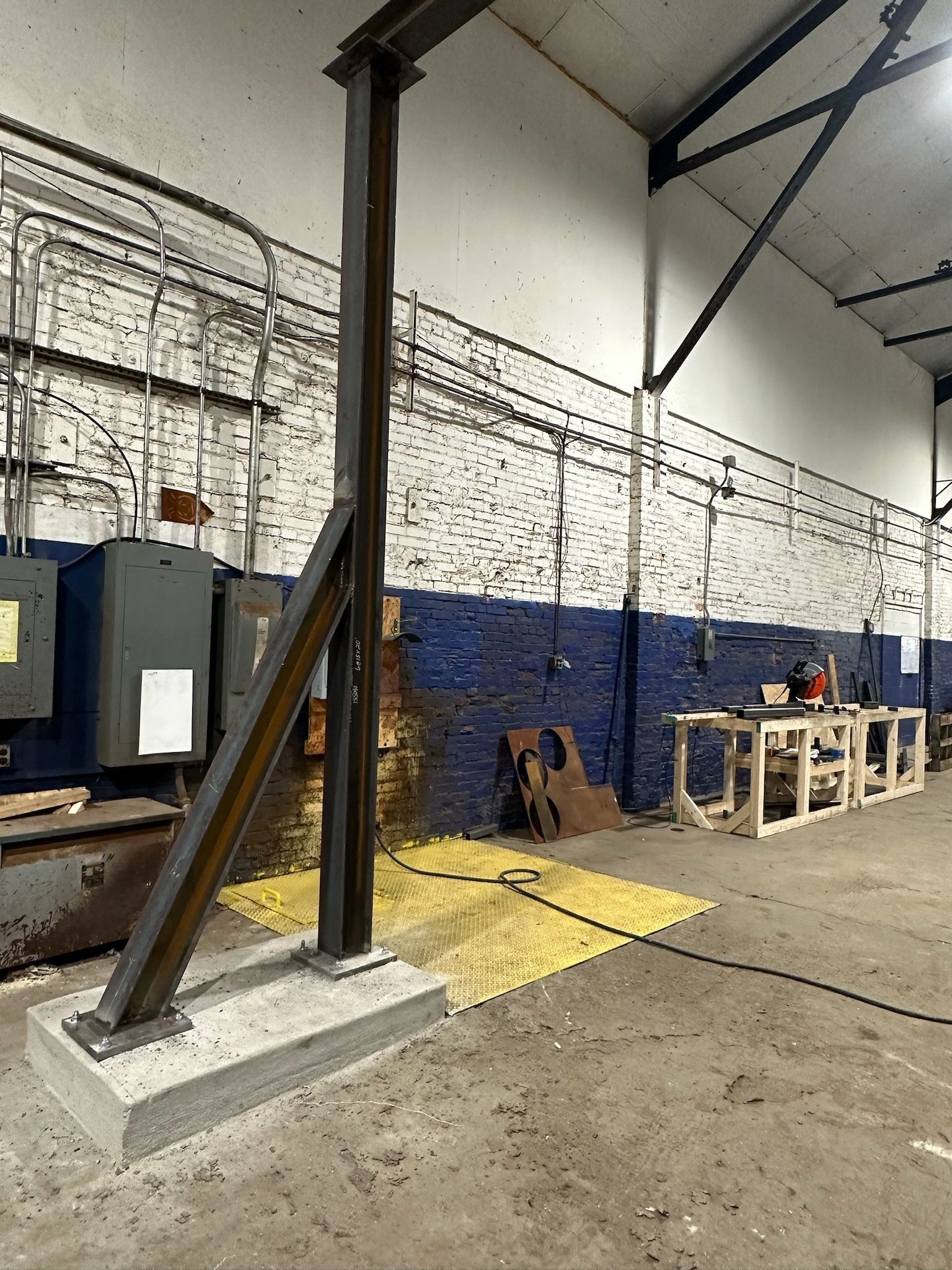 Steel support column bolted to concrete base in industrial setting.