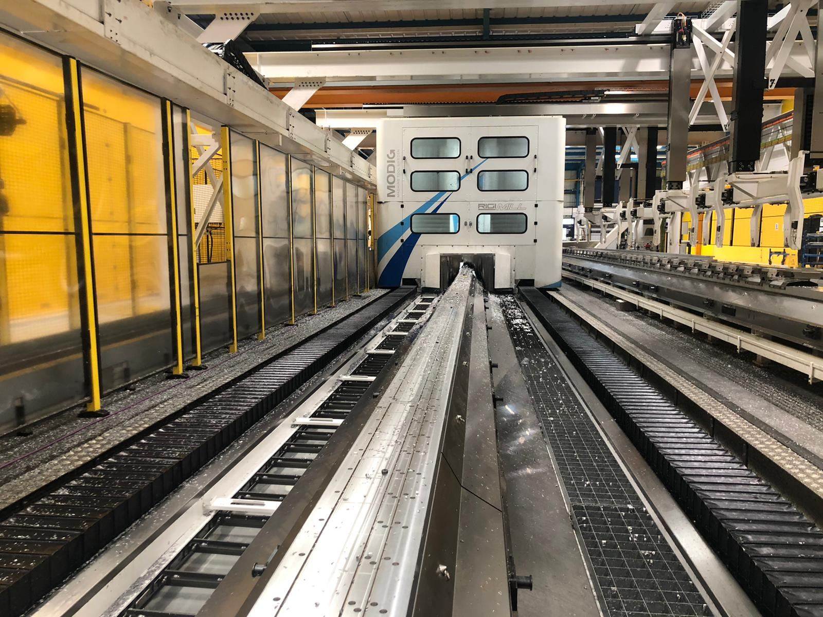 An automated train on a track in a maintenance facility. White train car with blue accents.