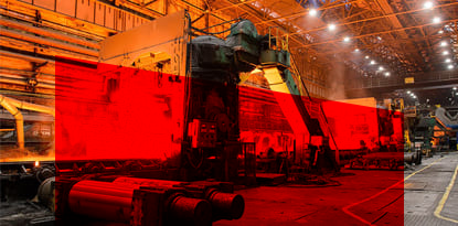 Industrial setting with machinery and red-hot steel coils.
