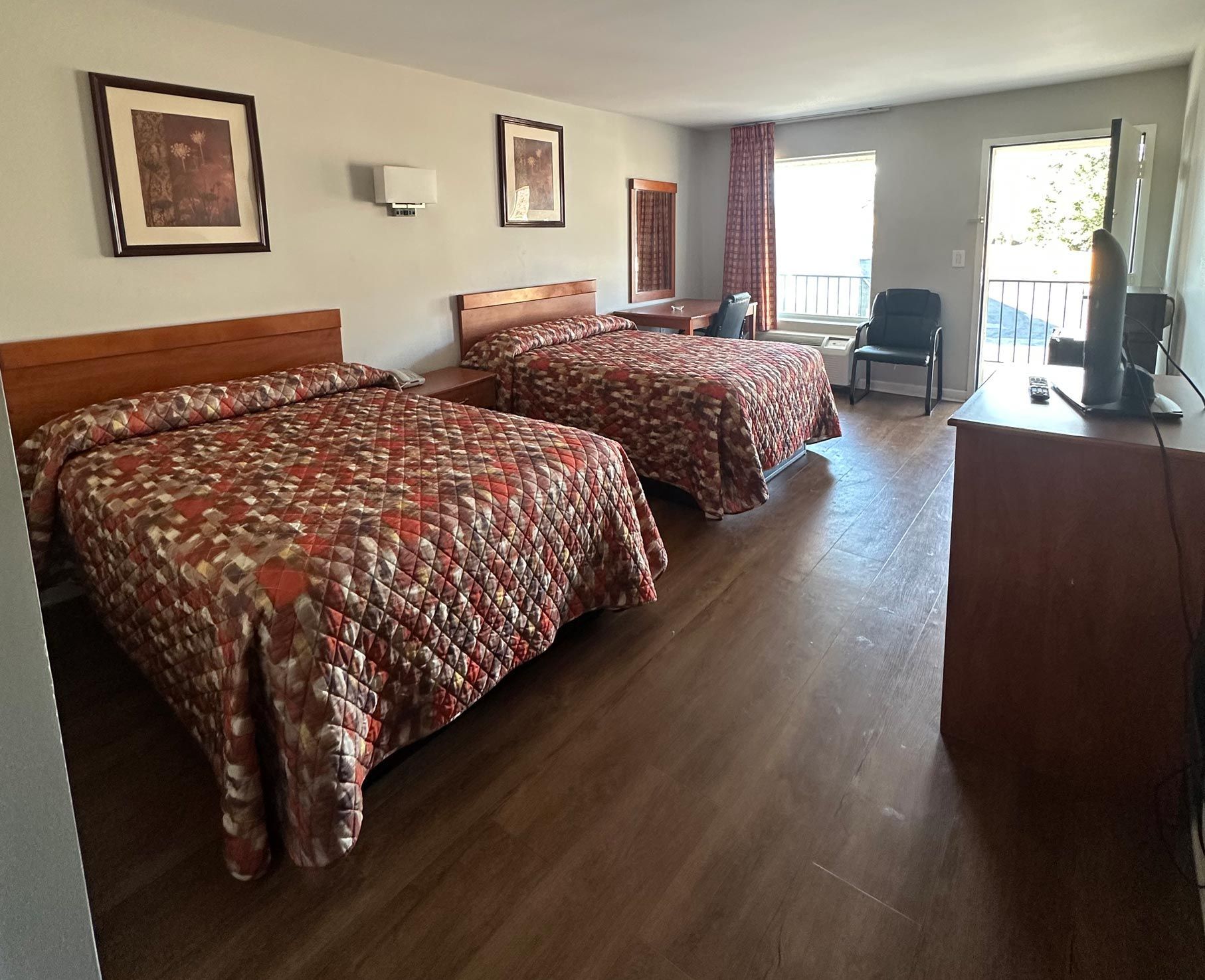 A motel room with two beds and a flat screen tv