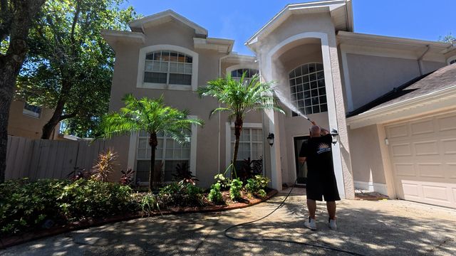 Person soft washing  a home