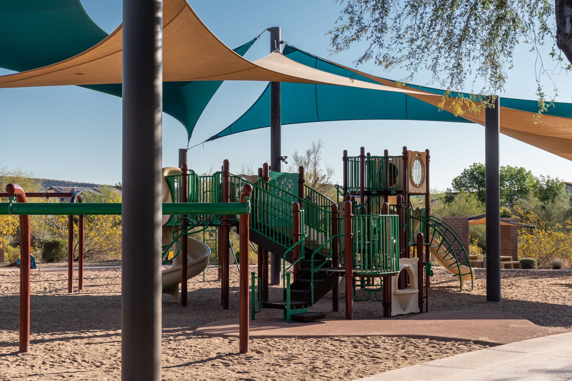 A playground shaded in the hot sun by canvas shade sails.
