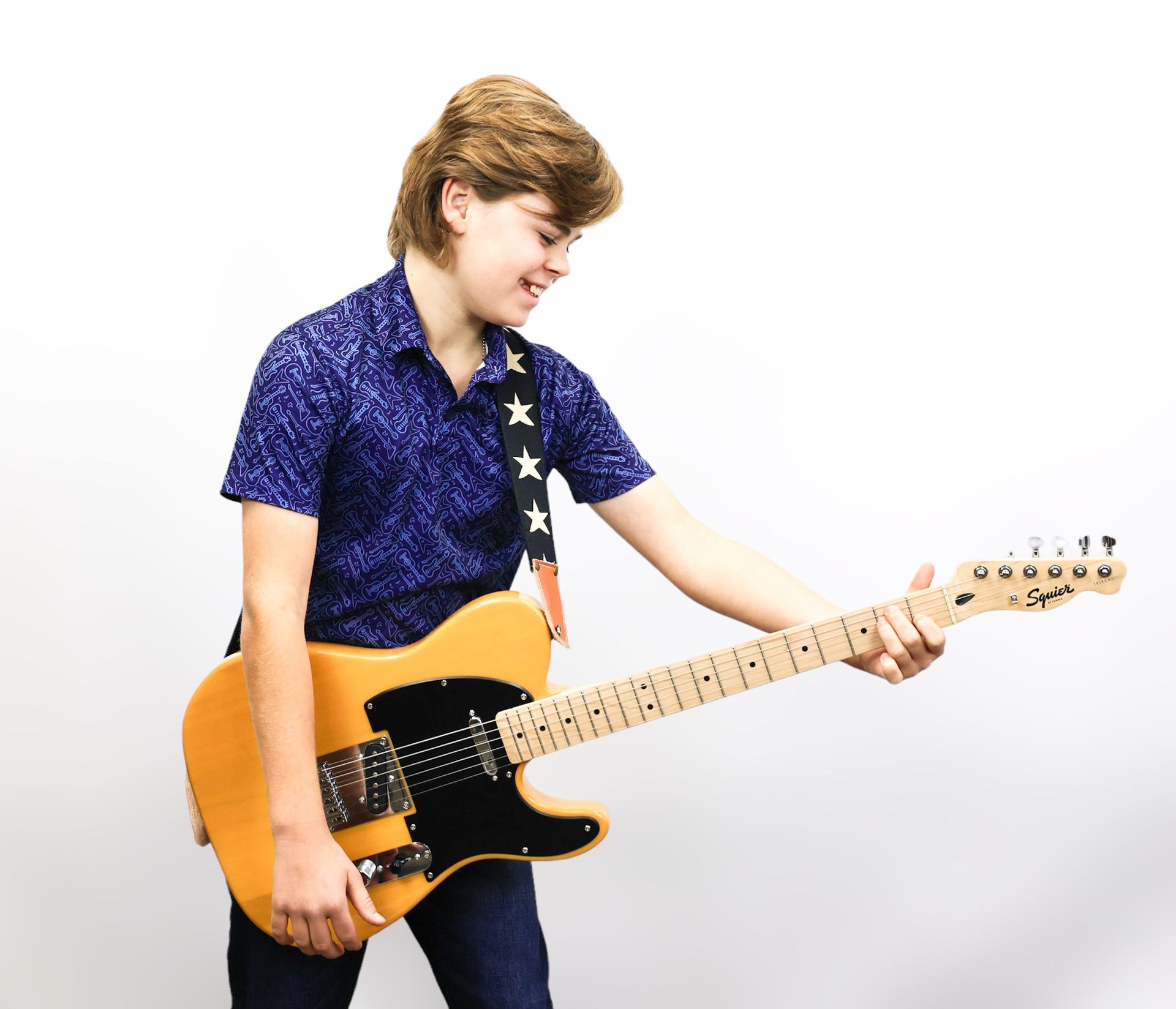 A young boy is playing an acoustic guitar in front of a man.