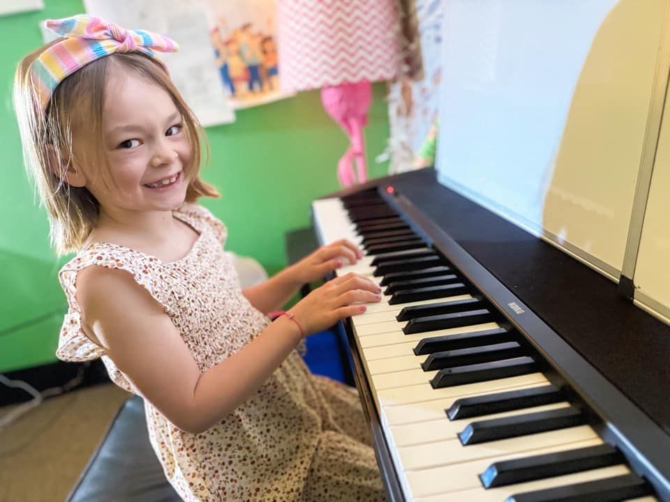 A young girl is sitting in front of a piano