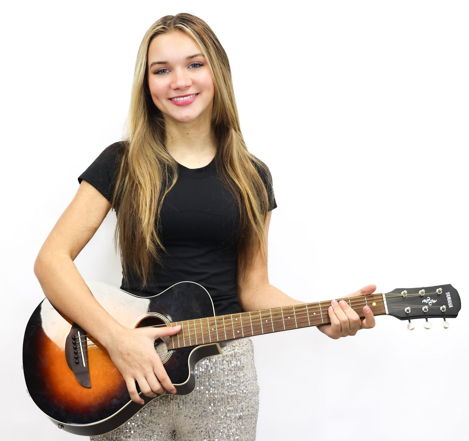 A woman in a black shirt is holding an acoustic guitar