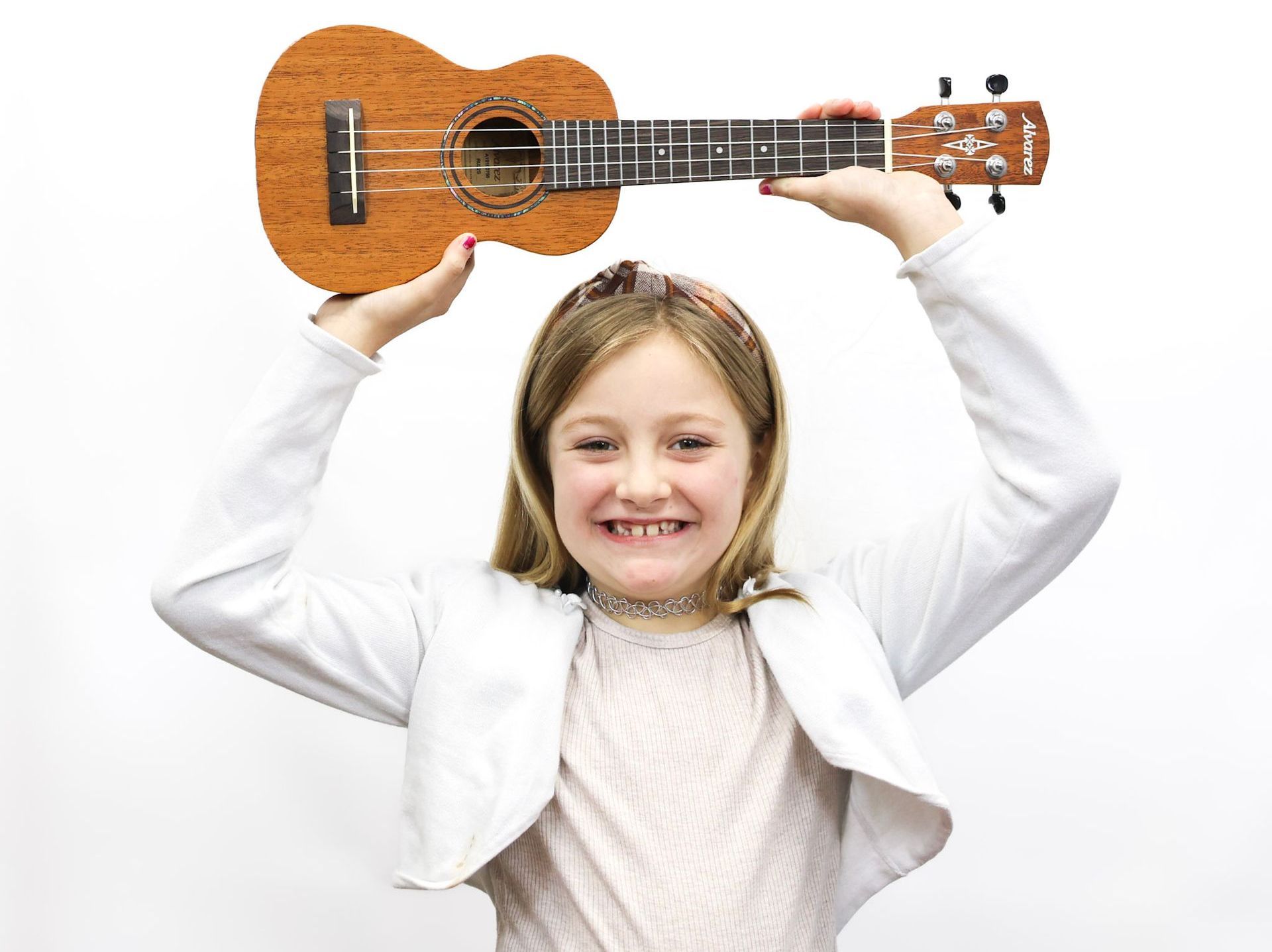 A young girl is holding a guitar over her head