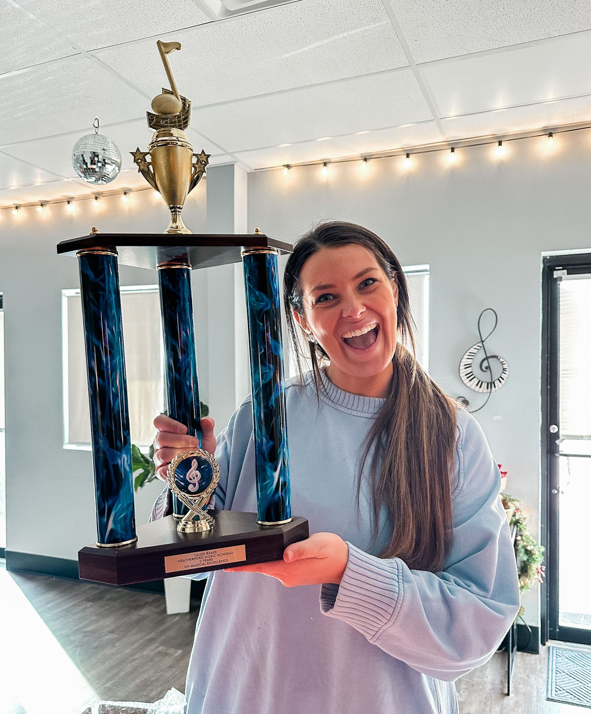 A young girl is standing in front of a trophy wall.