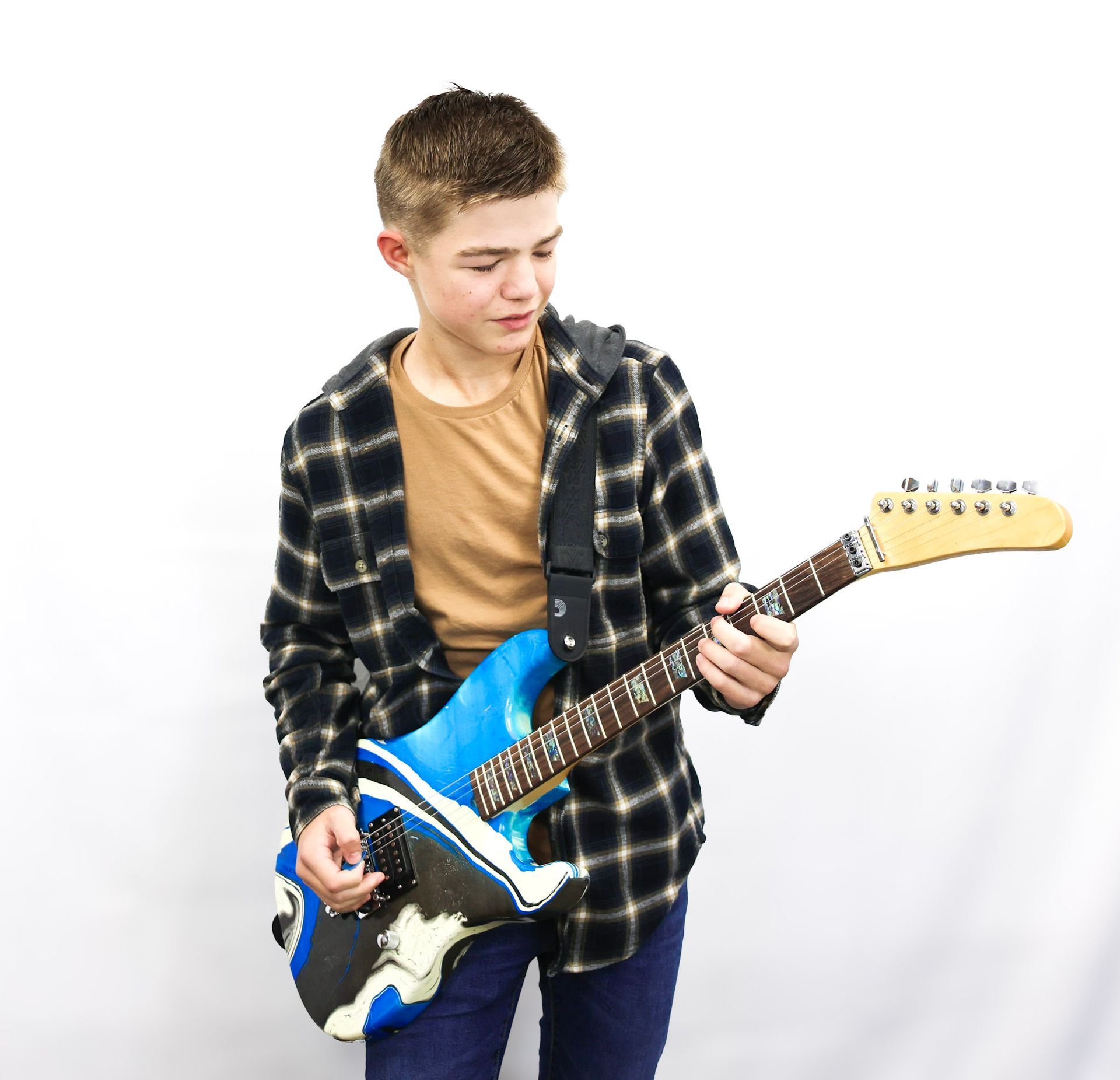 A young man in a plaid shirt is holding a blue electric guitar