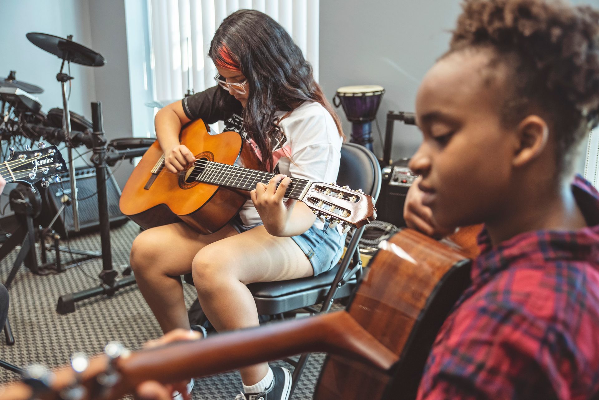 Two young girls are playing guitars in a room.