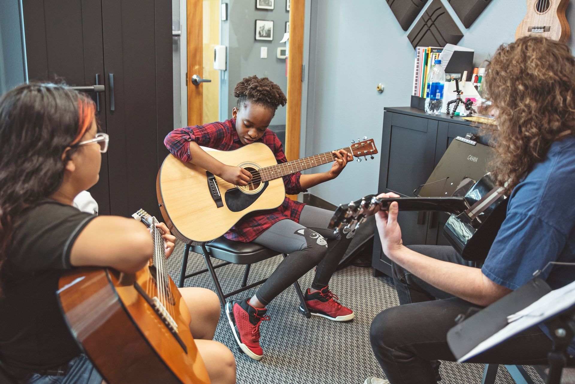A group of people are playing guitars in a room.