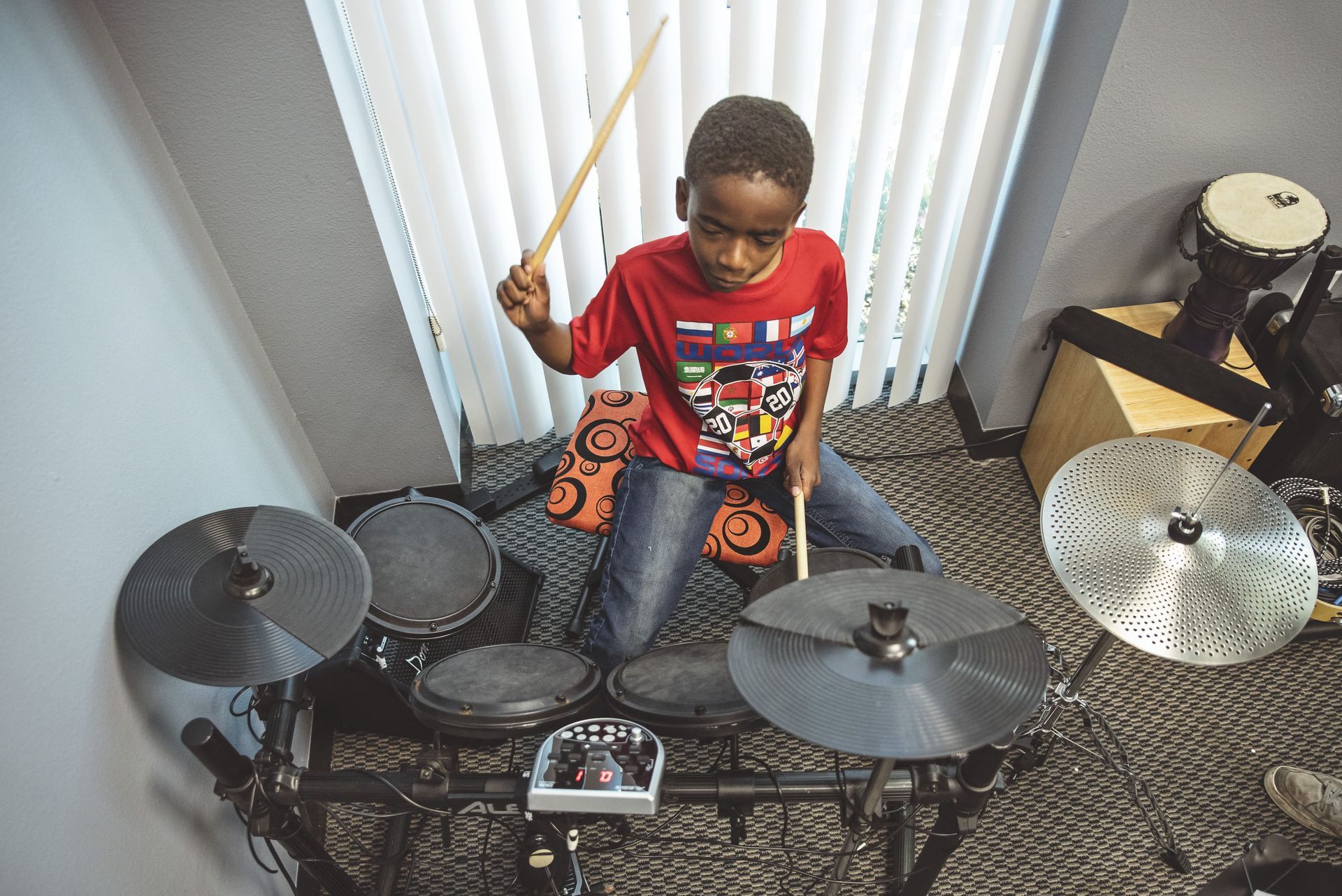 A young boy is playing drums in a room.