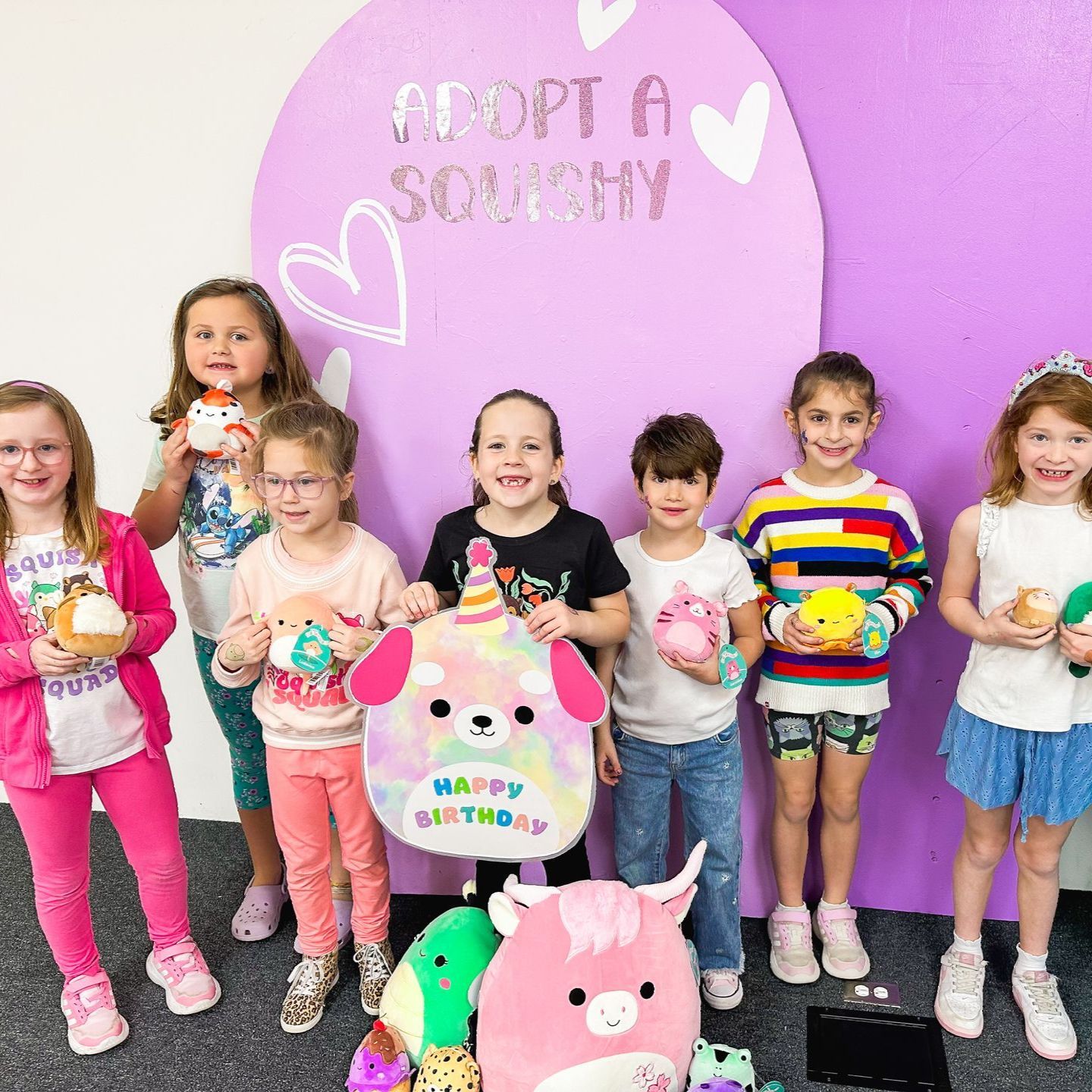 A group of young girls are standing next to each other holding stuffed animals.