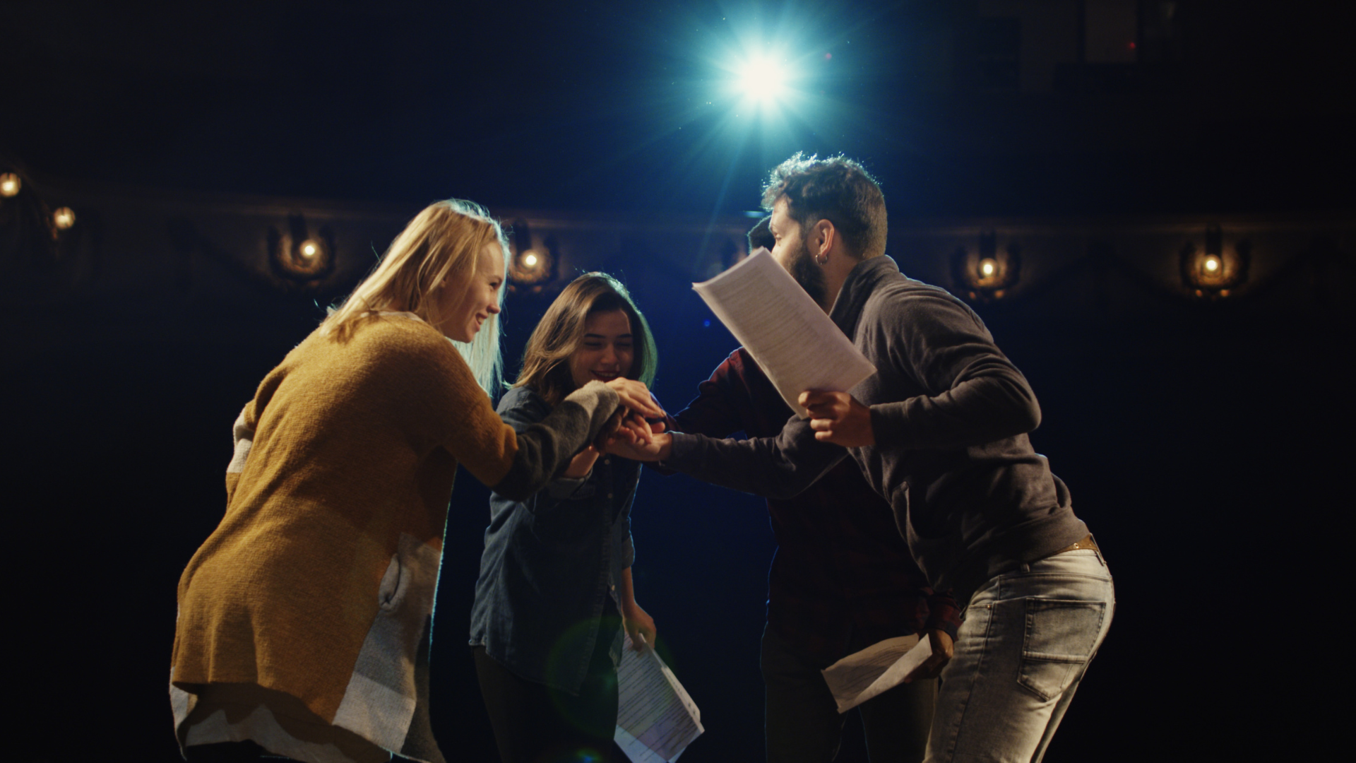 Three women are playing guitars and singing into a microphone.