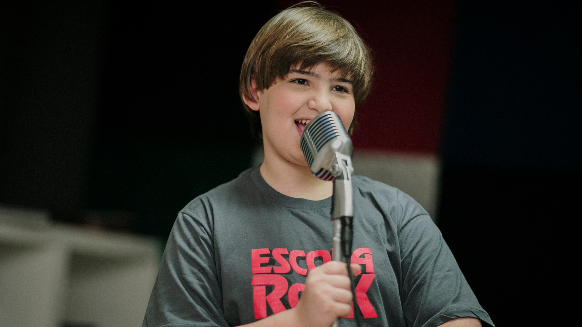 Two young girls are singing into microphones in a recording studio.