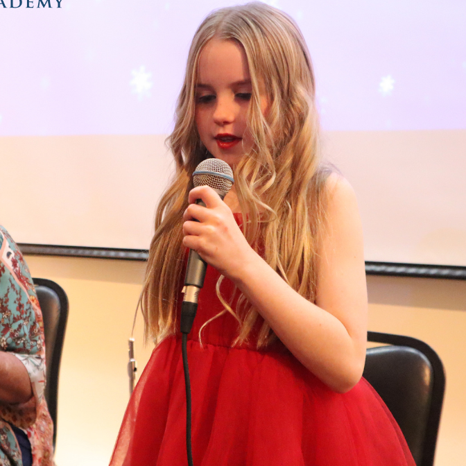A girl in a red dress is singing into a microphone
