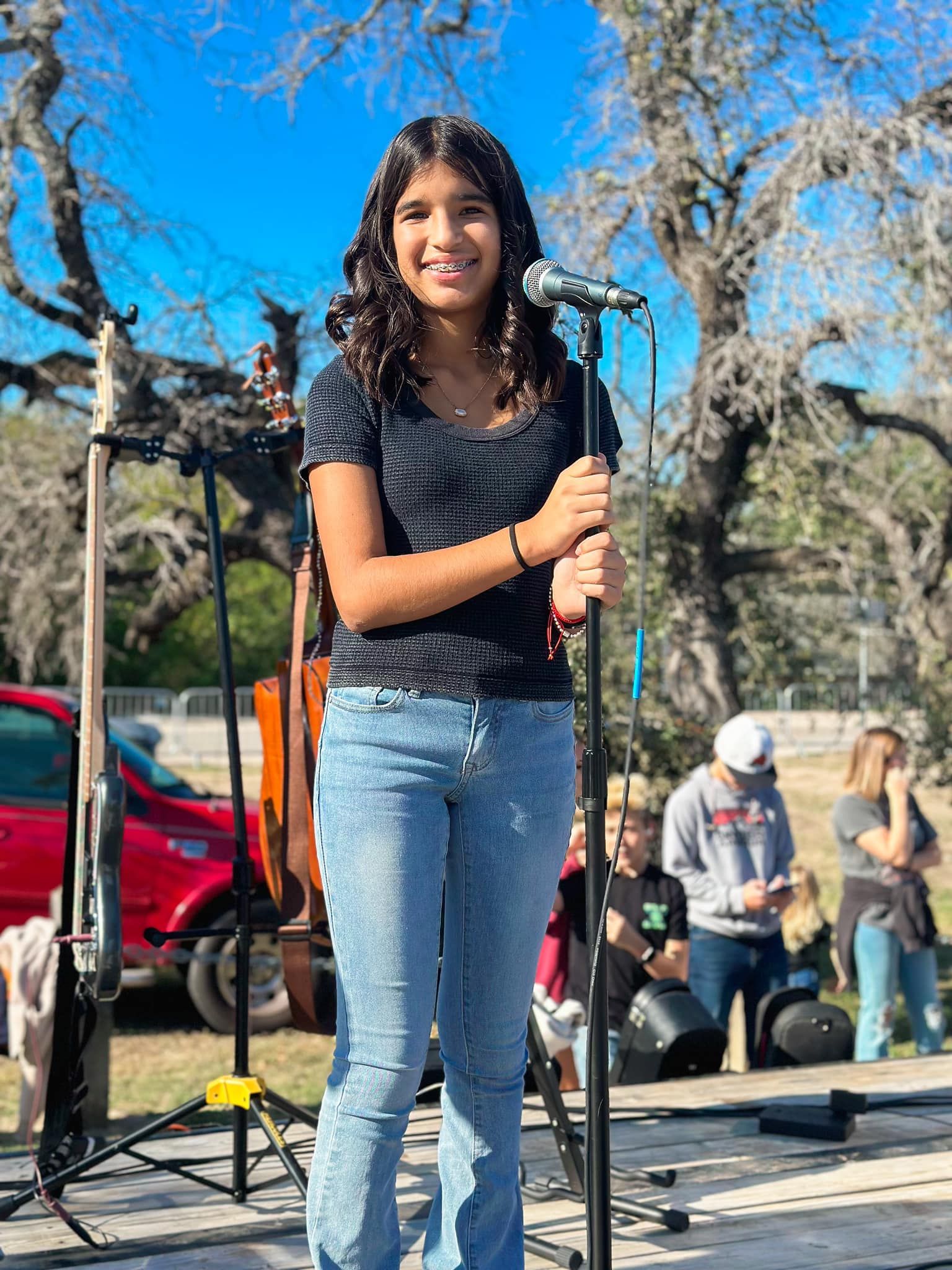 A young boy is making a rock and roll sign in front of a drum set.