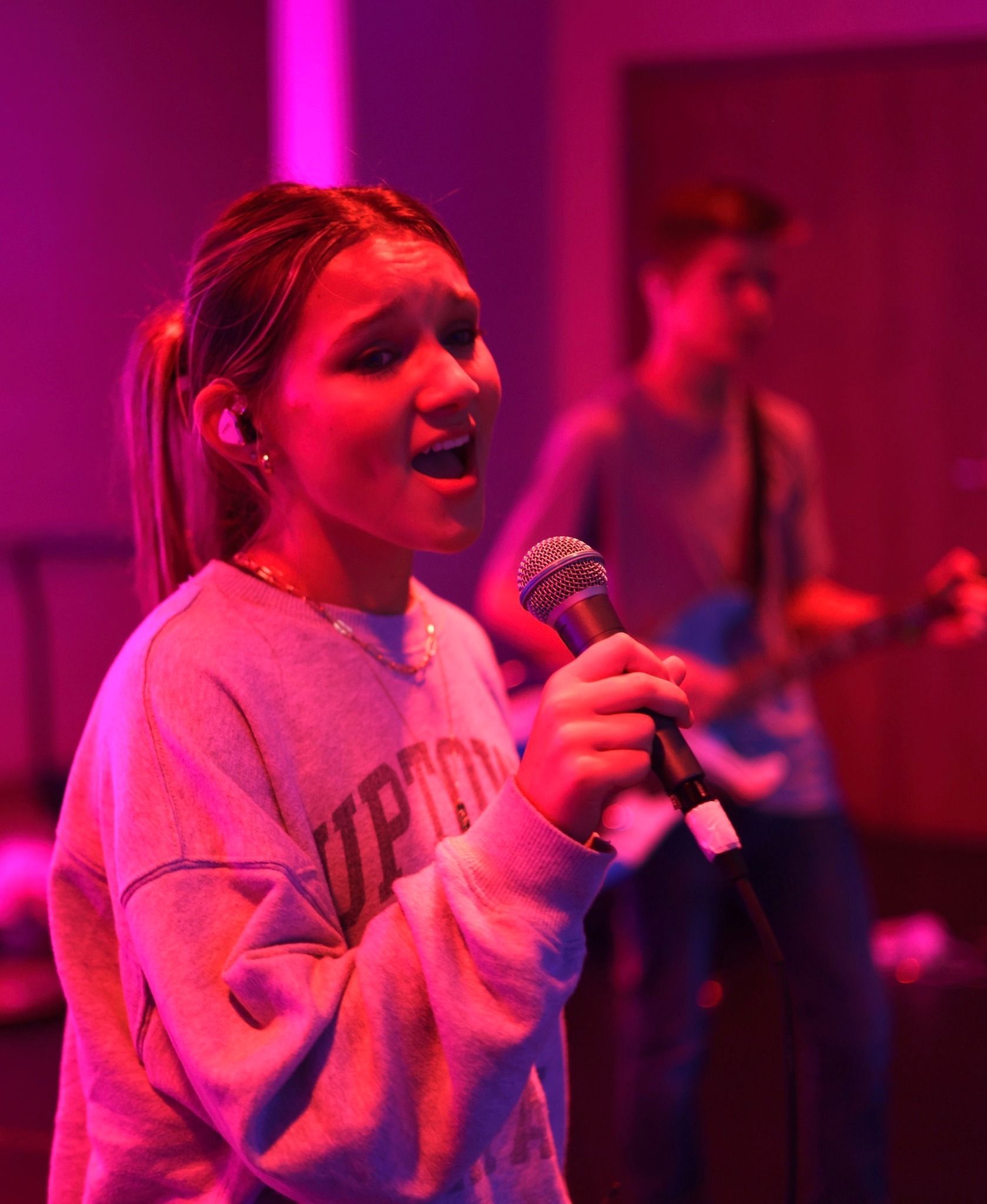 A little girl is playing drums in a dark room.