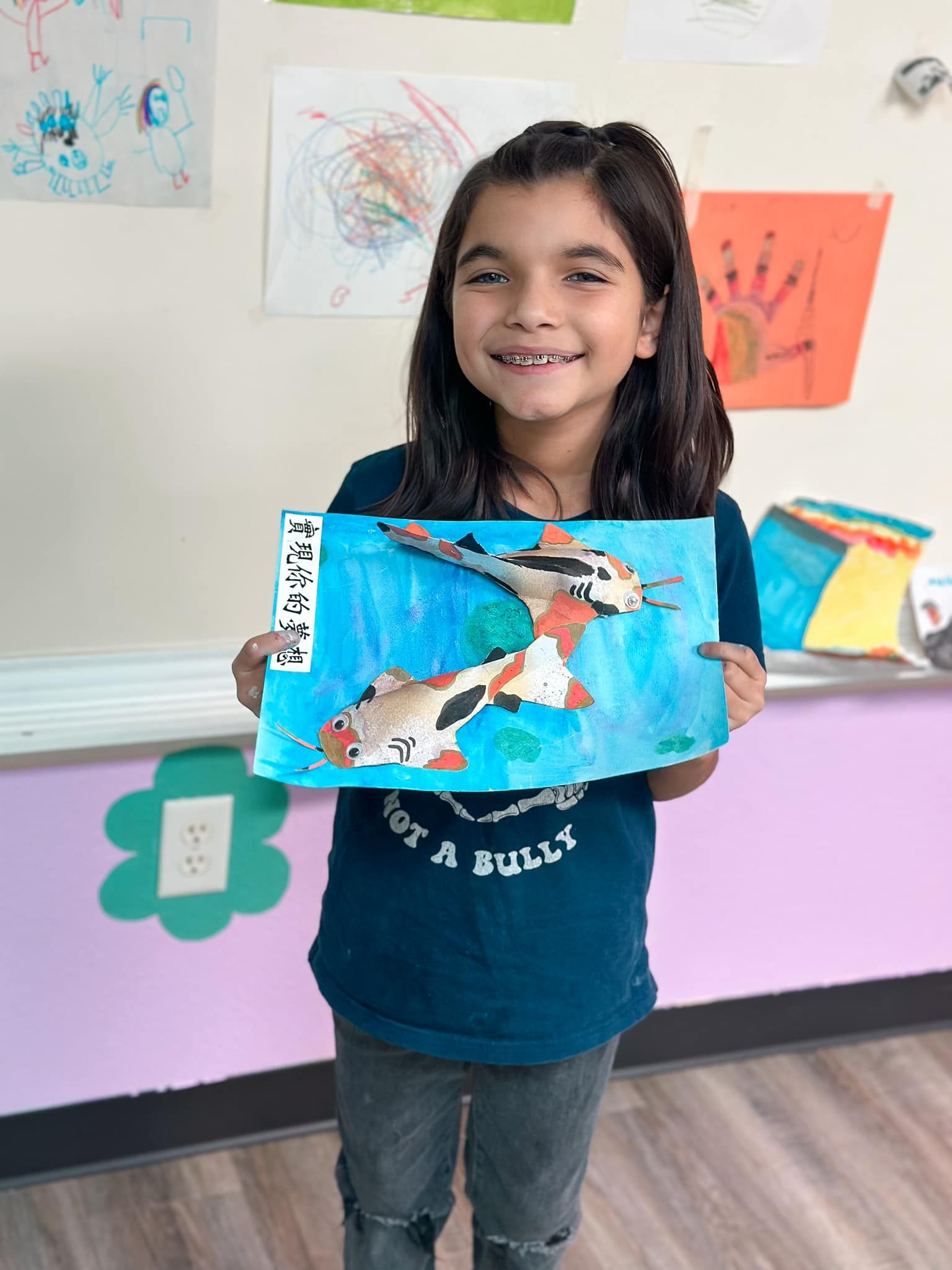 A young girl is standing in front of a trophy wall.