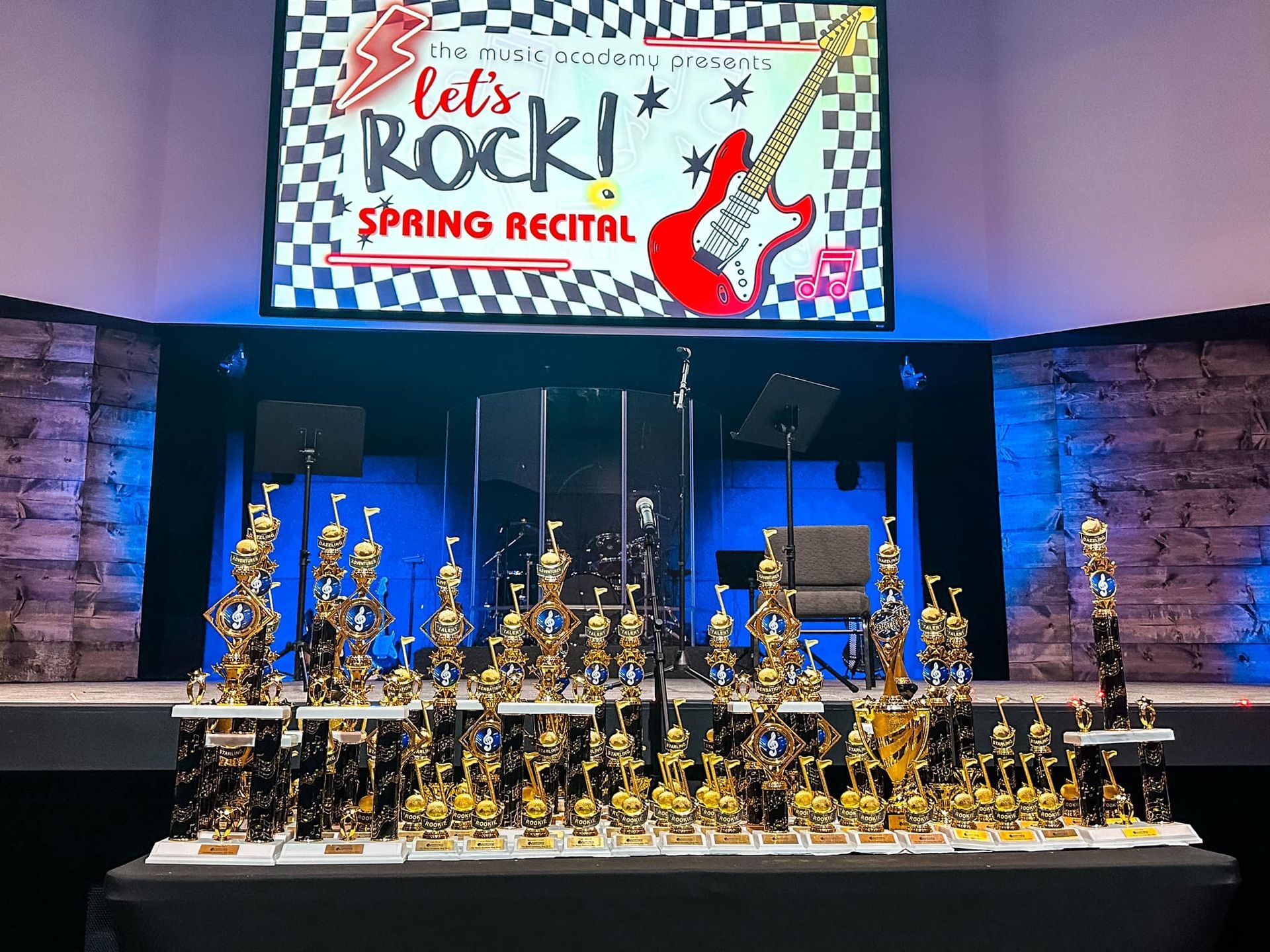 A stage with trophies and a sign that says `` let 's rock spring recital ''.