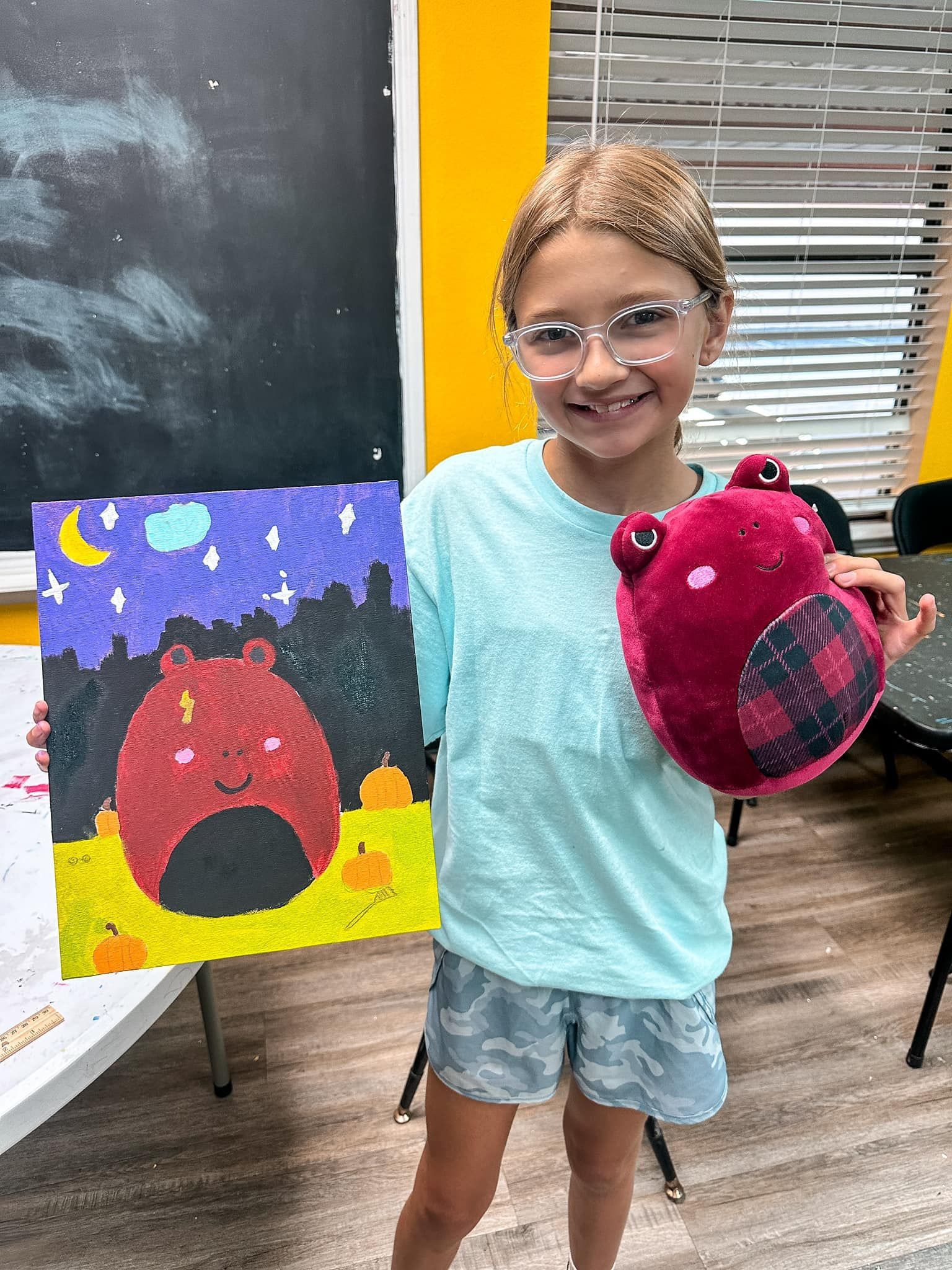 A woman and a girl are standing next to each other holding a trophy.