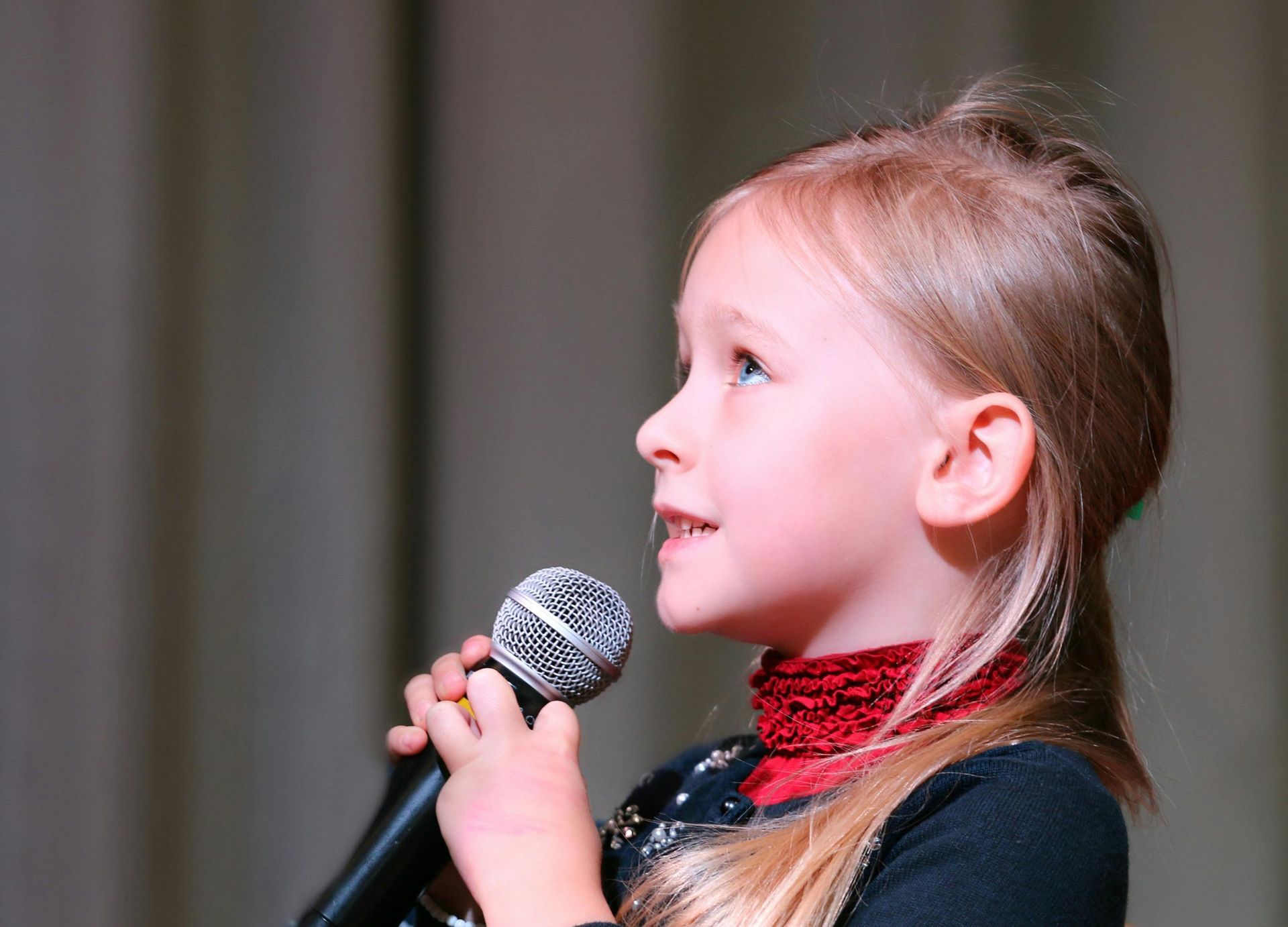 A little girl is holding a guitar in a room.