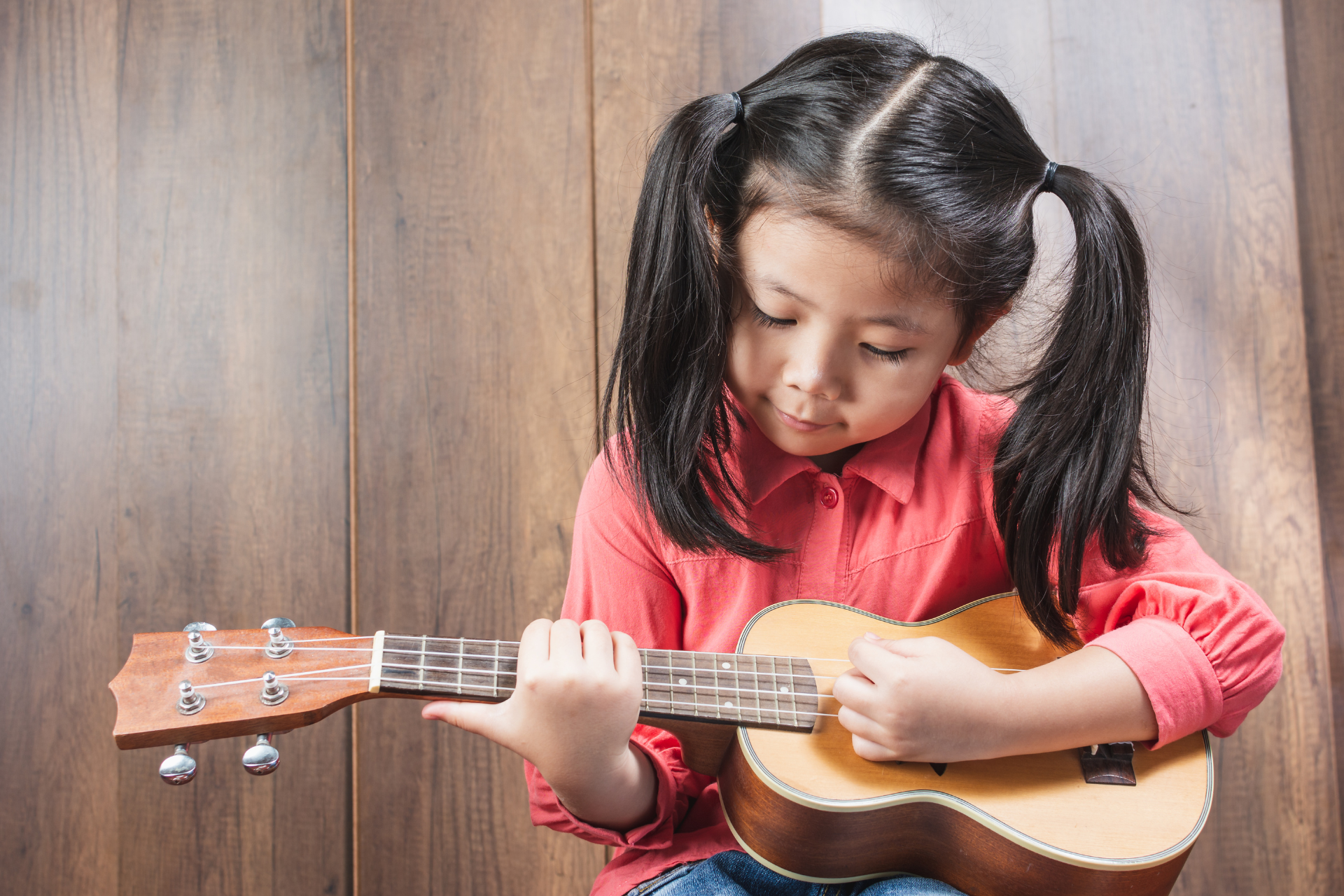 A woman is playing a ukulele and a boy is playing a piano.