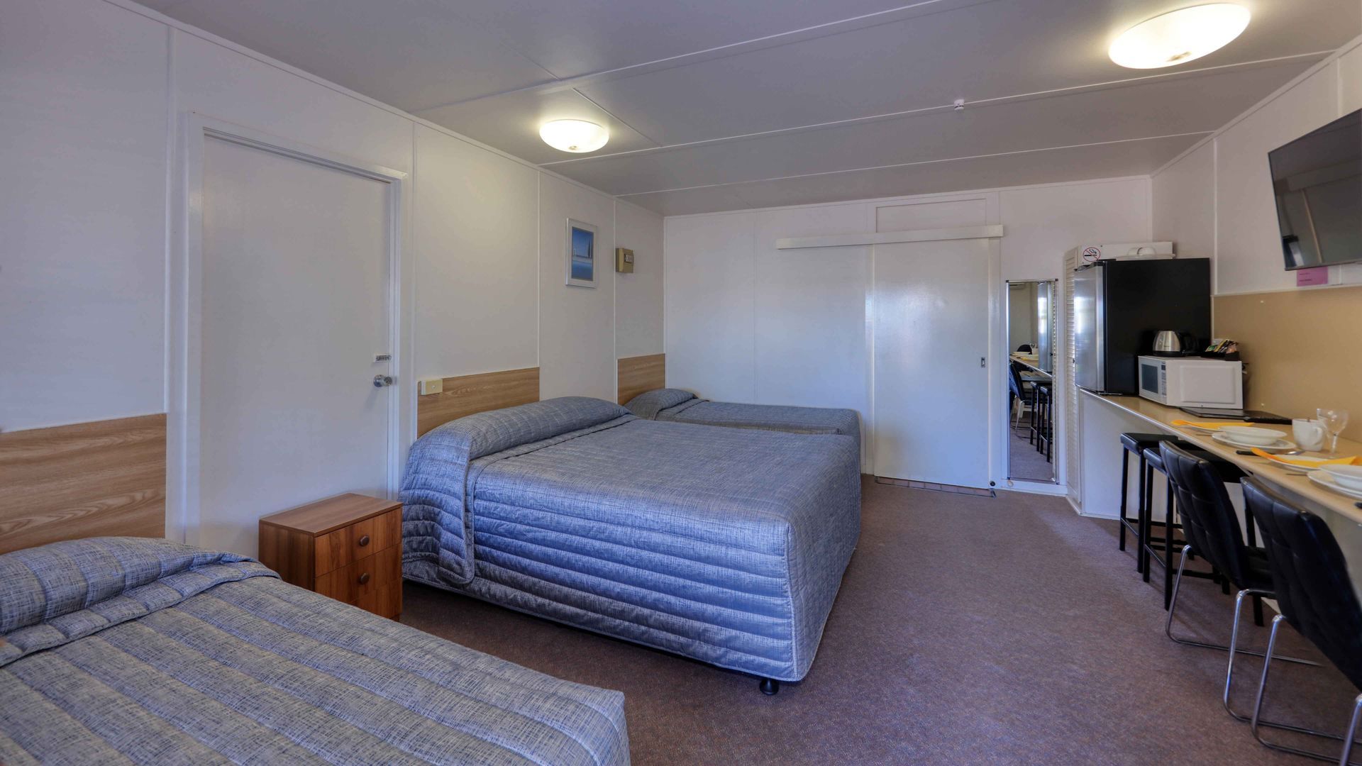 A hotel room with two beds , a desk and a microwave.