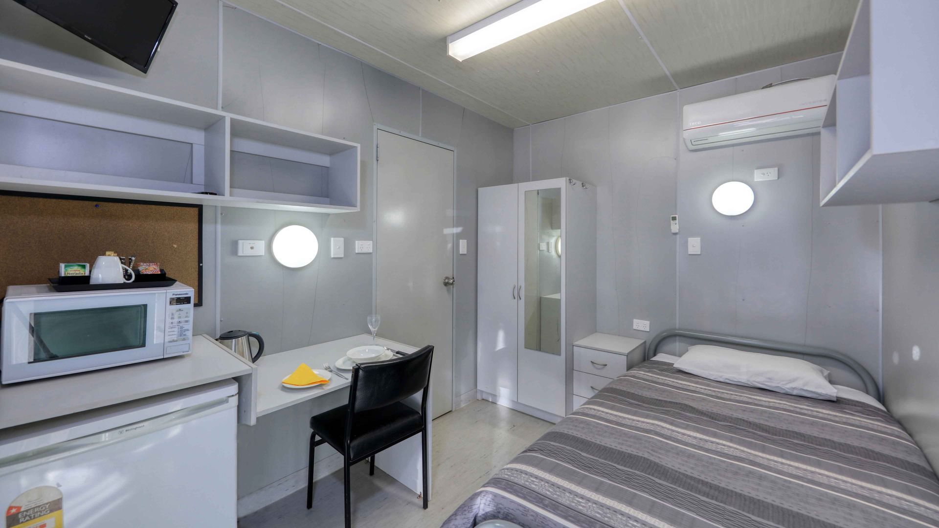 A bedroom with a bed , desk , chair and microwave.