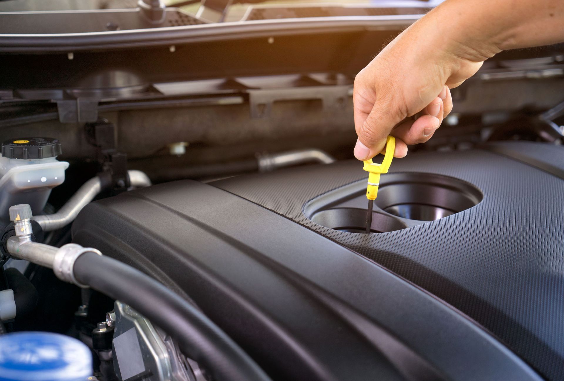 Car mechanic holding dipstick for checking engine oil level