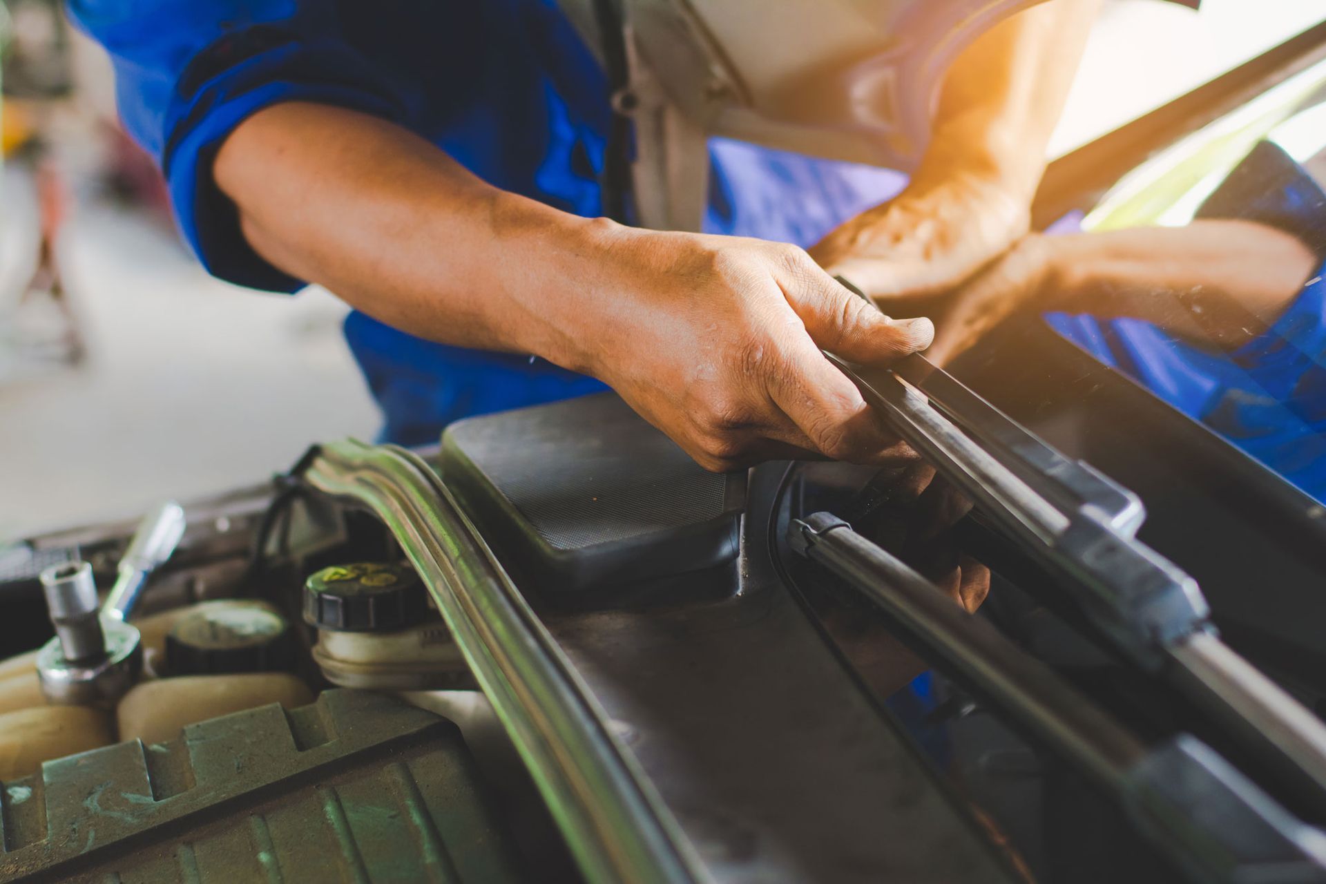 technician changing windscreen wipers on a car station