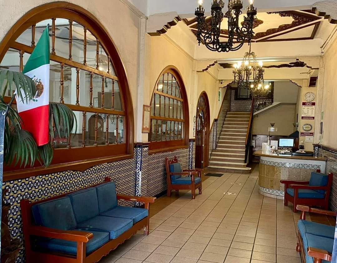Un vestíbulo con un sofá, sillas y una bandera mexicana.