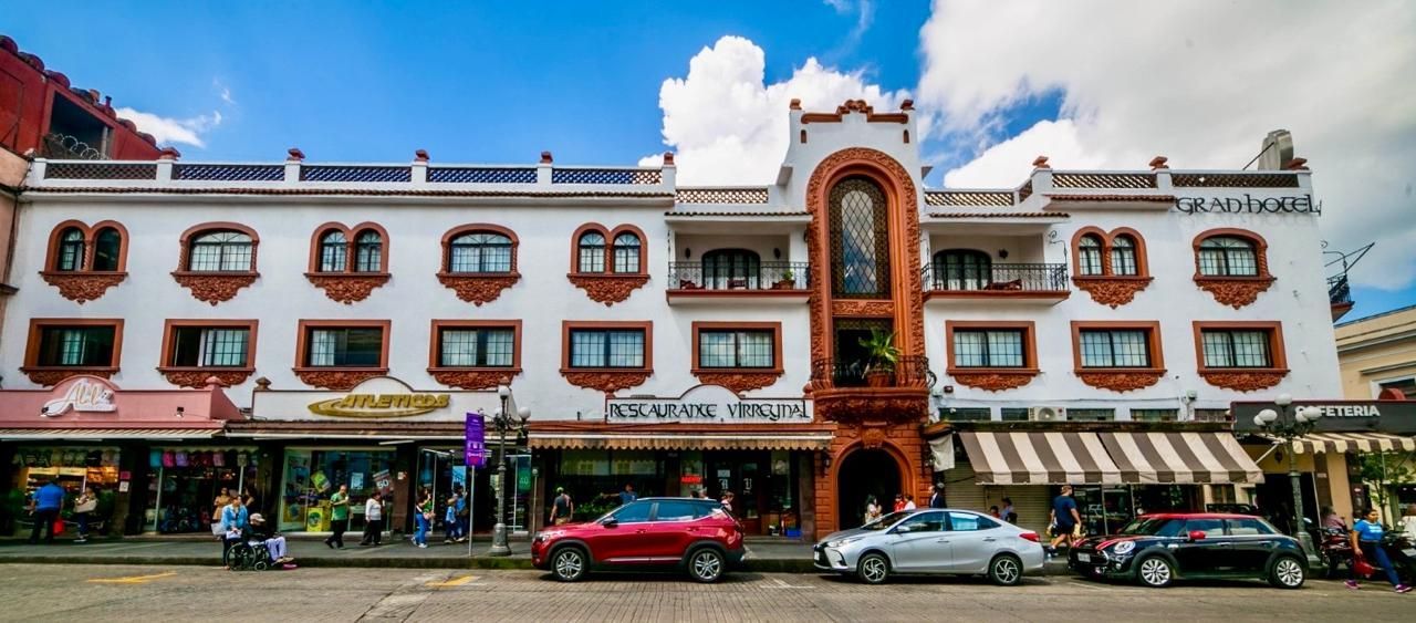 Un gran edificio blanco con muchas ventanas y coches aparcados delante de él.