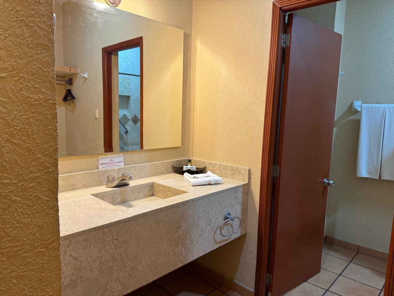 Un baño en una habitación de hotel con lavabo y espejo.