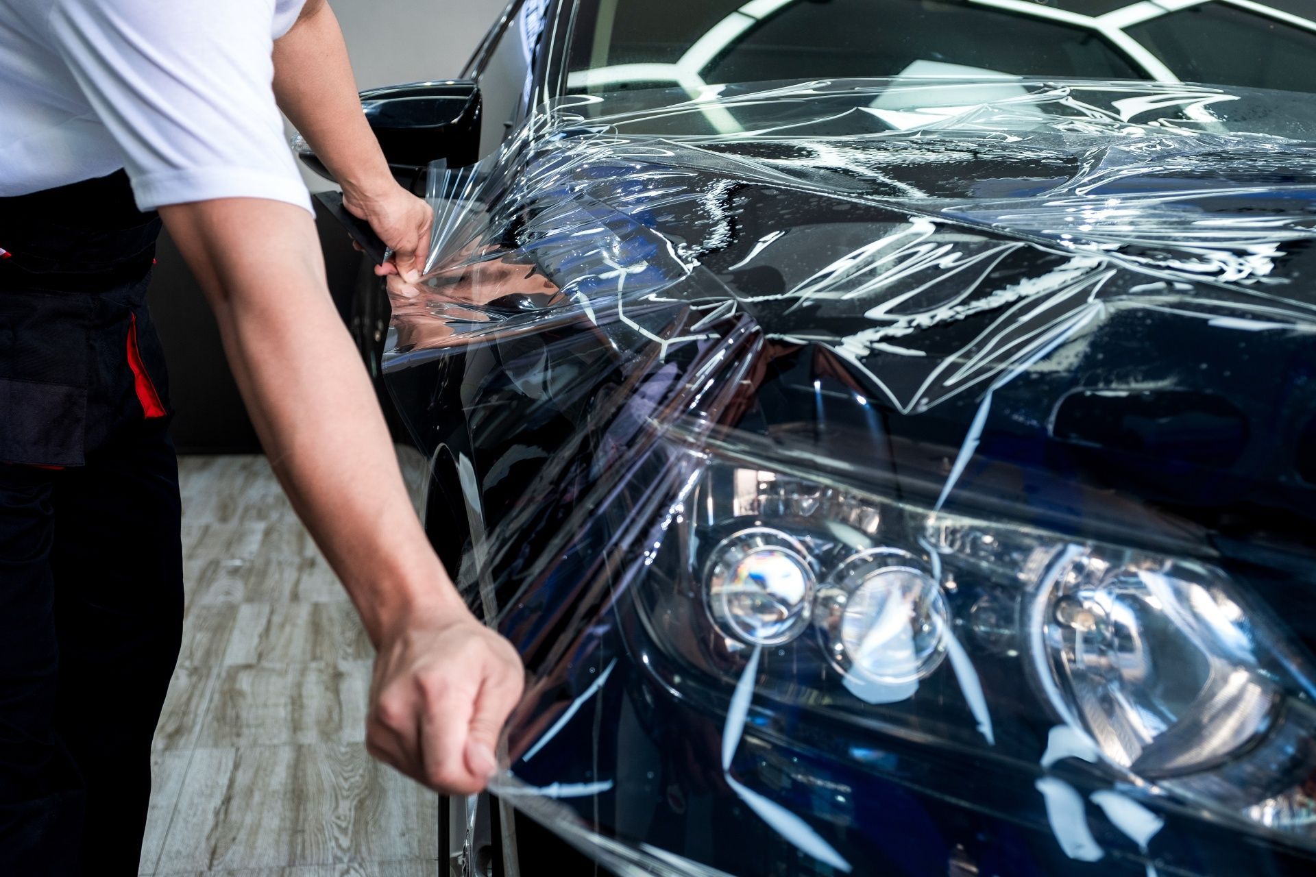 A man is wrapping a car with plastic wrap.