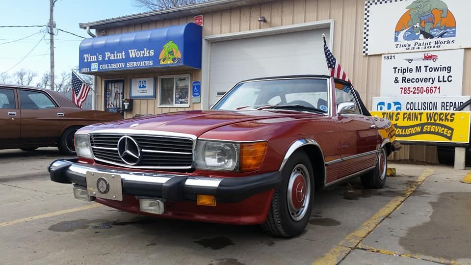 A red mercedes benz is parked in front of a building.