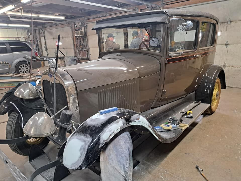 An old car is being restored in a garage.