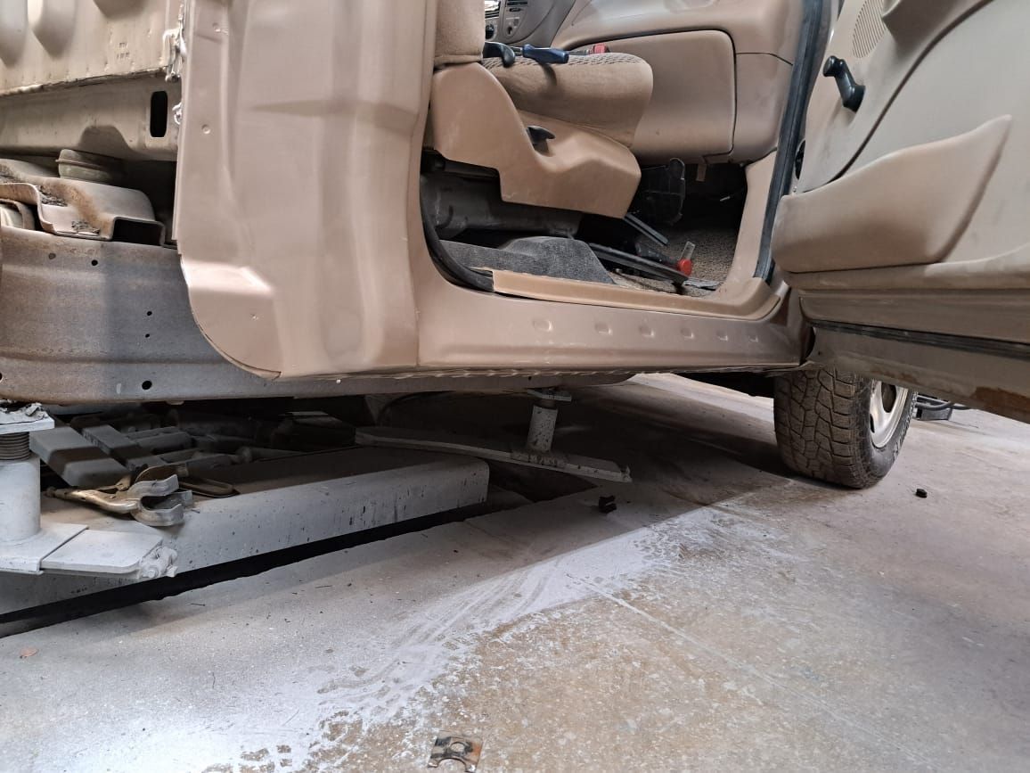 A car is sitting on a lift in a garage with the door open.