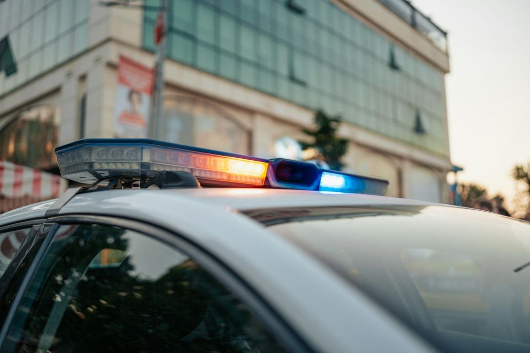 A police car is parked in front of a building with its lights on.