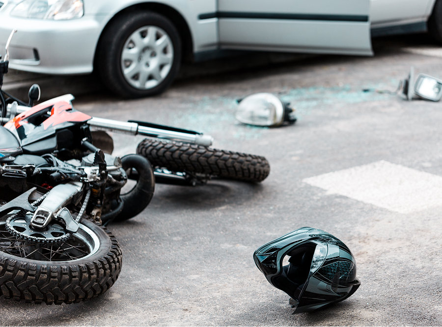 A motorcycle is laying on the ground next to a car.