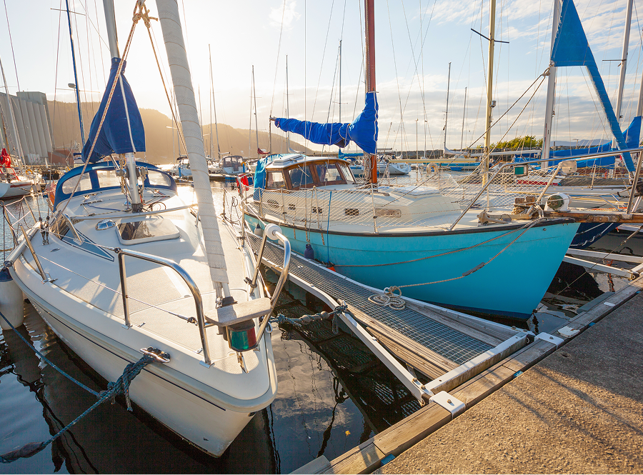 Two sailboats are docked next to each other in a marina.