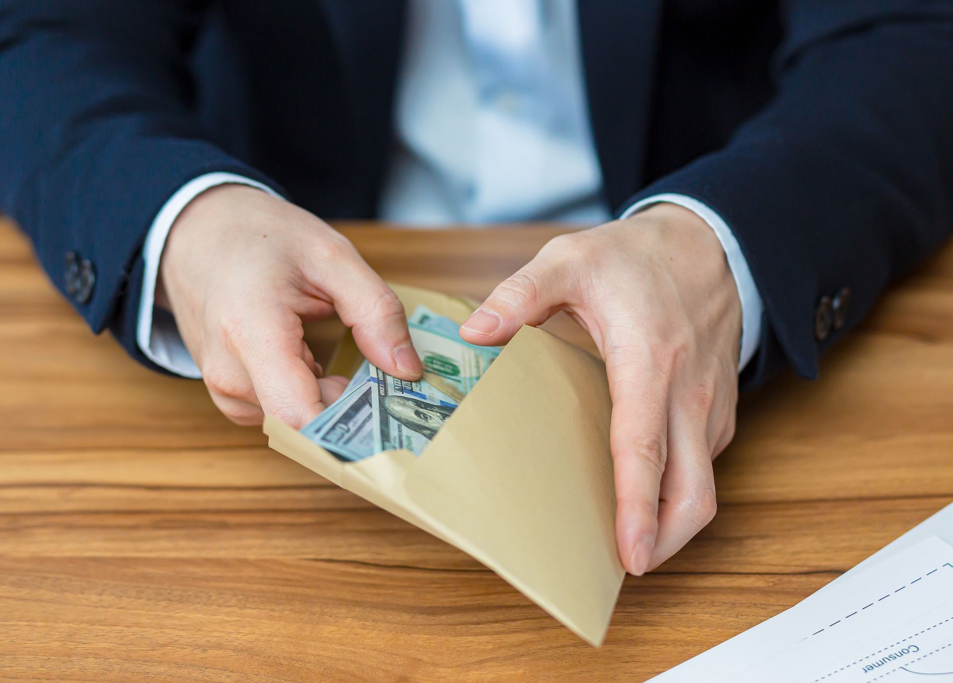 A man in a suit is putting money in an envelope.