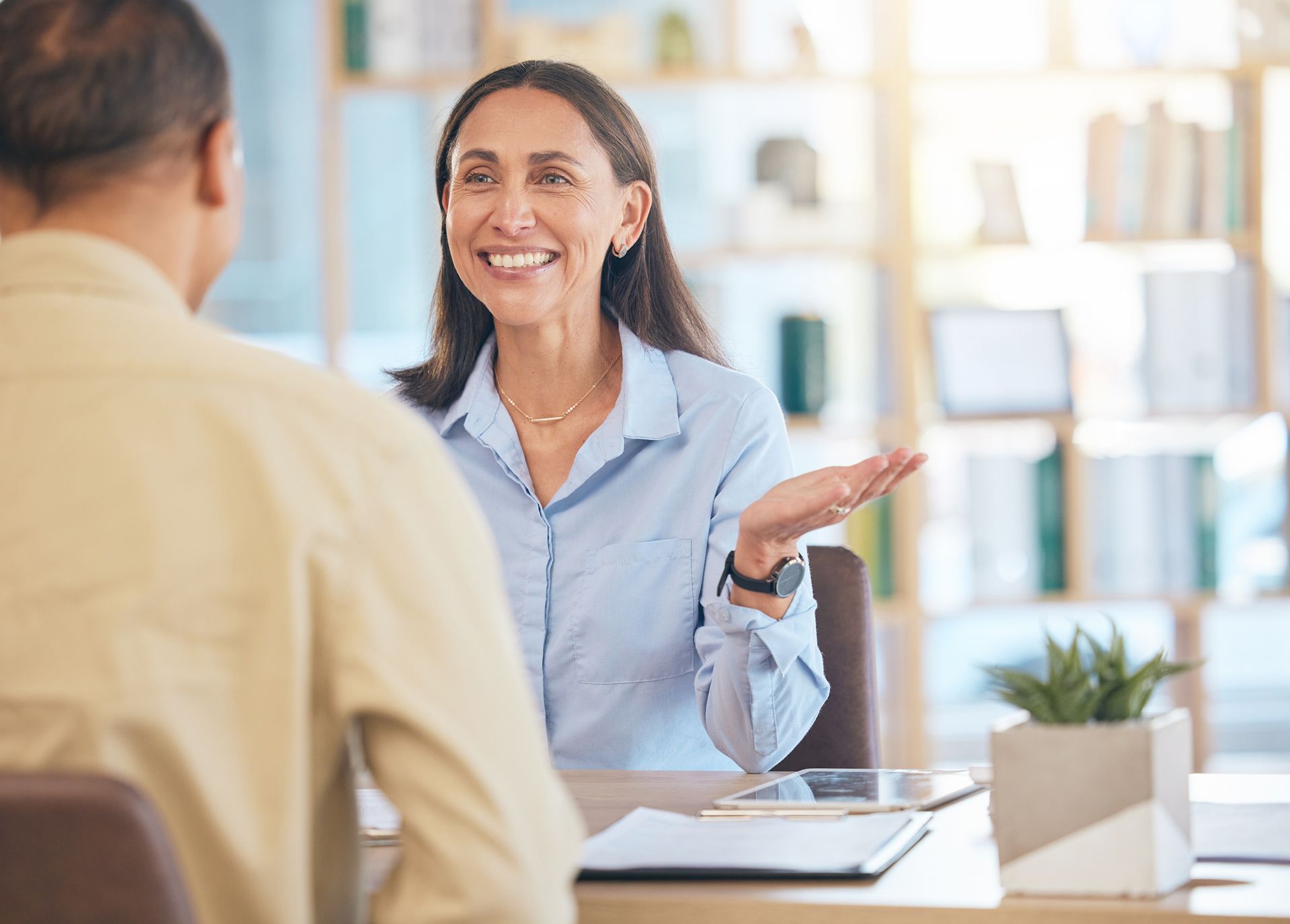 A woman is sitting at a table talking to a man.