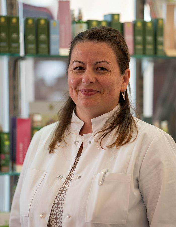 Eine Frau in einem weißen Laborkittel lächelt in die Kamera.