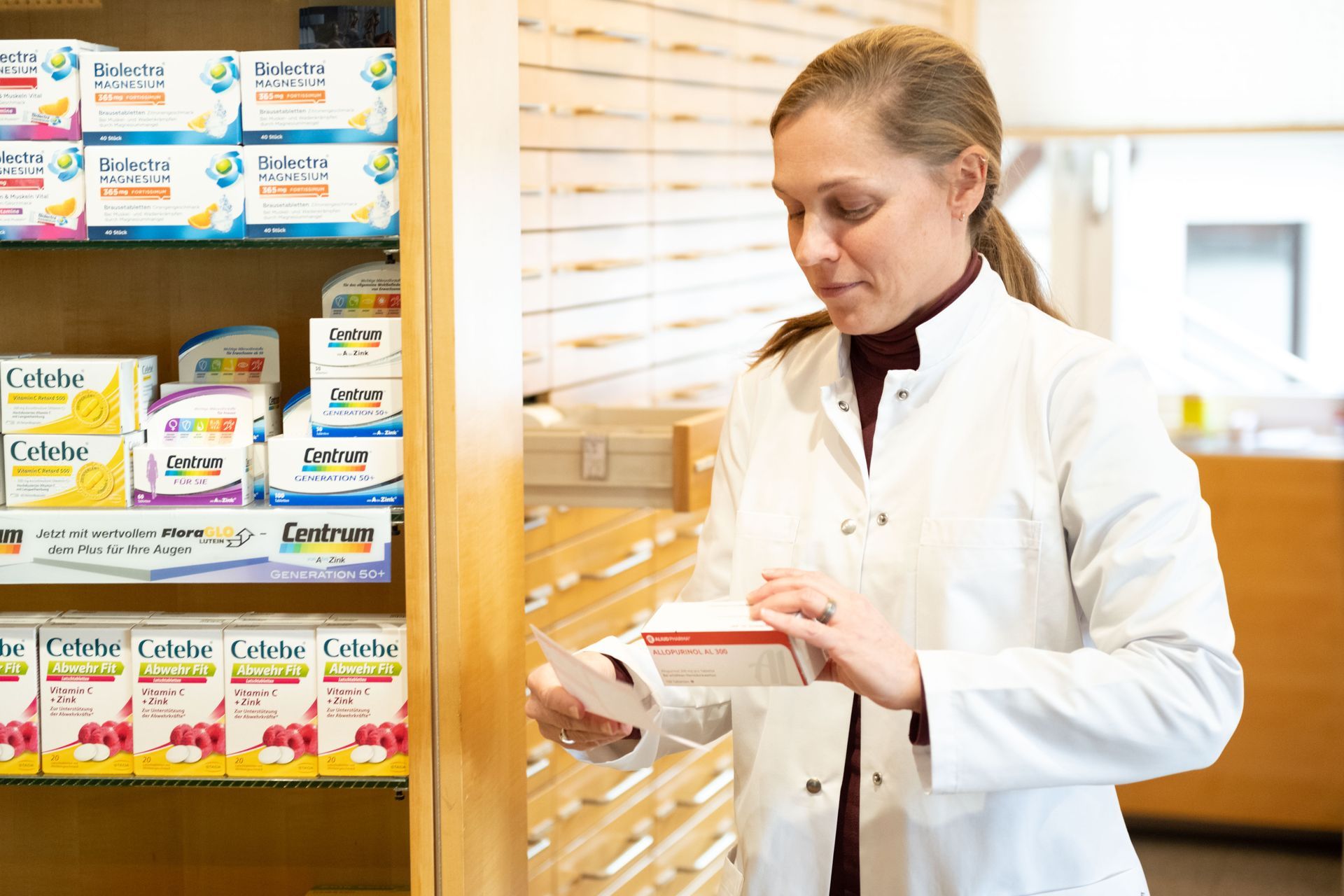 Eine Apothekerin schaut sich in einer Apotheke eine Schachtel Pillen an.