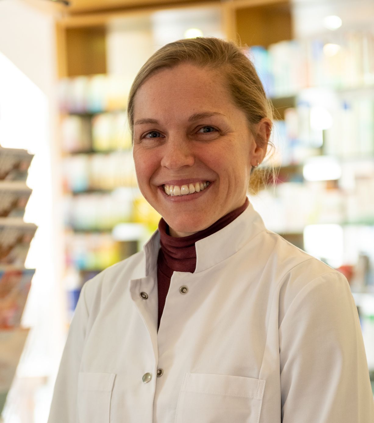 Eine Frau im weißen Laborkittel lächelt in die Kamera