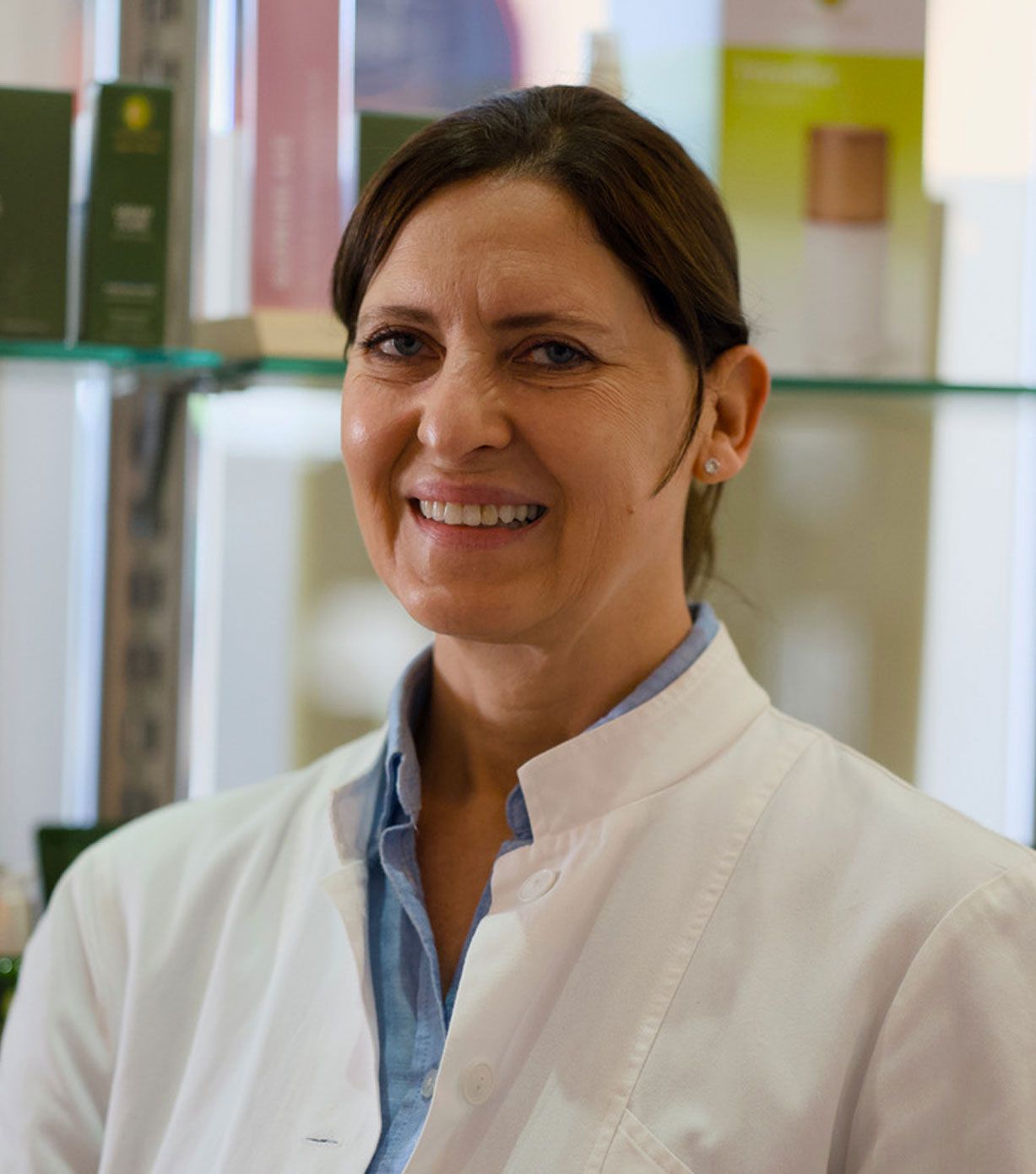 Eine Frau im weißen Laborkittel lächelt in die Kamera