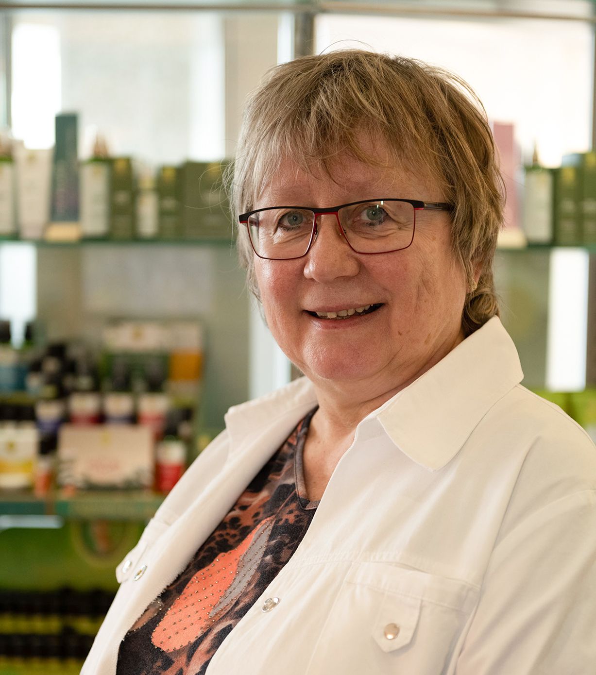 Eine Frau mit Brille und weißem Kittel lächelt in die Kamera