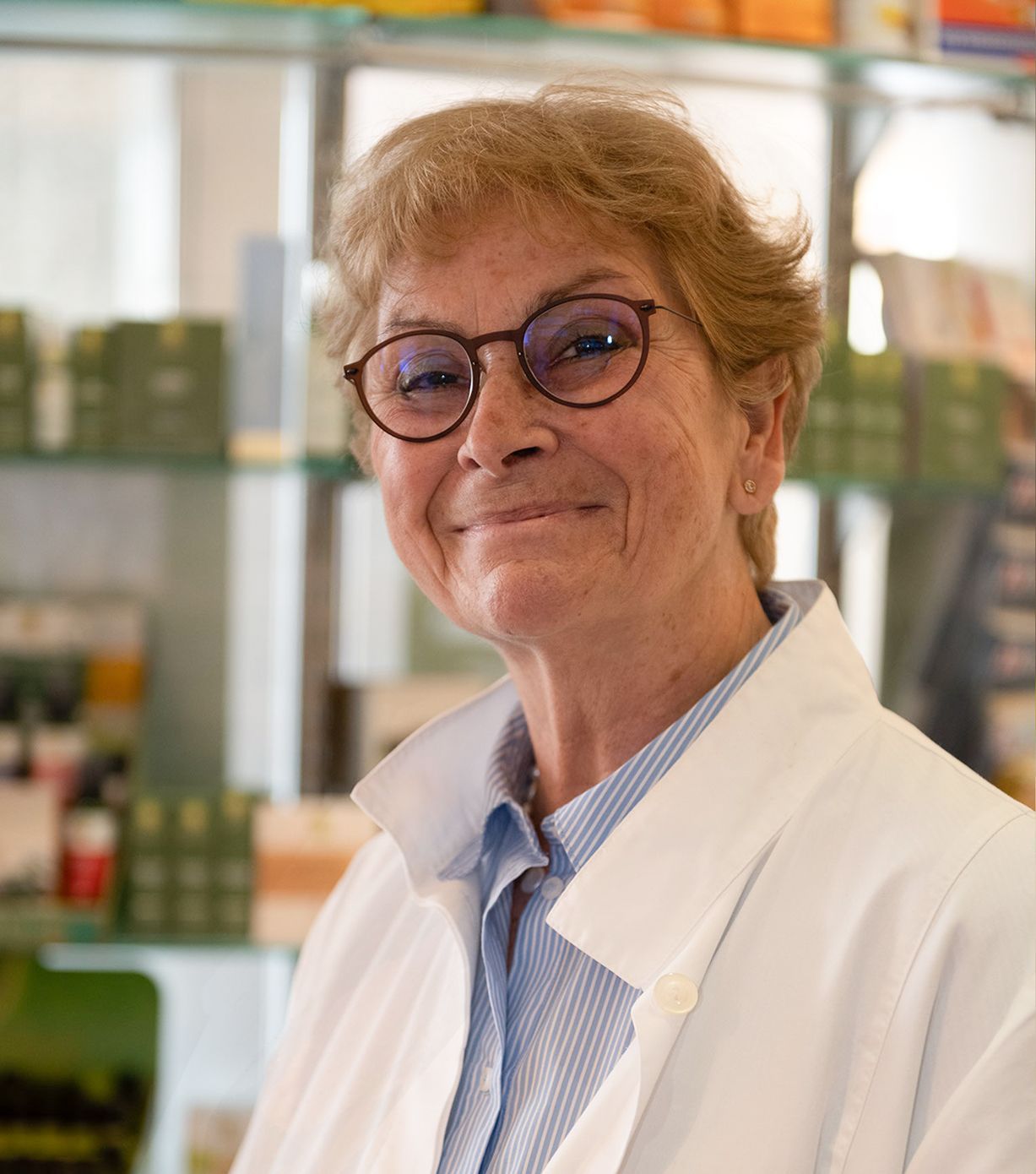 Eine Frau mit Brille und weißem Kittel lächelt in die Kamera