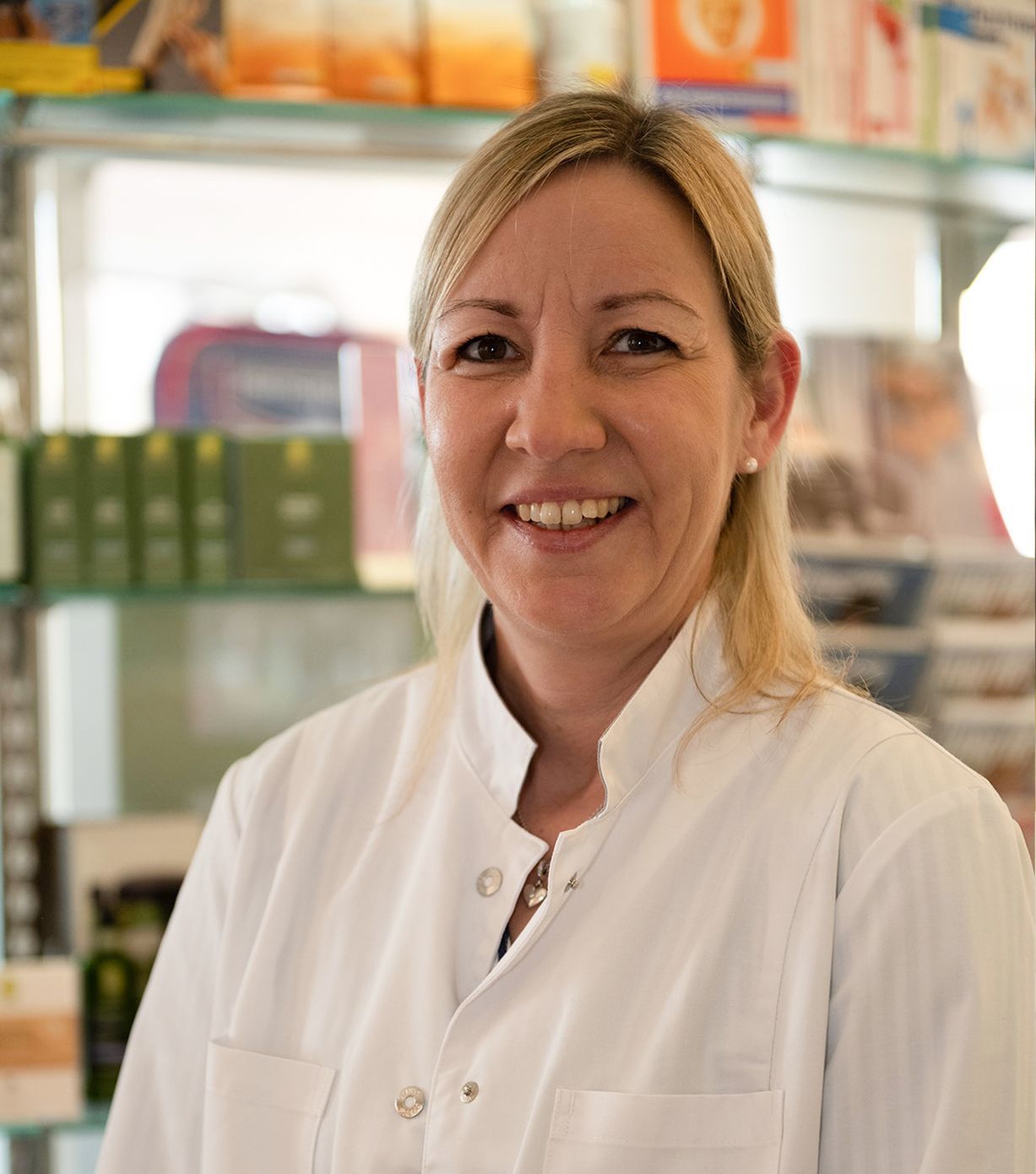 Eine Frau im weißen Laborkittel lächelt in die Kamera